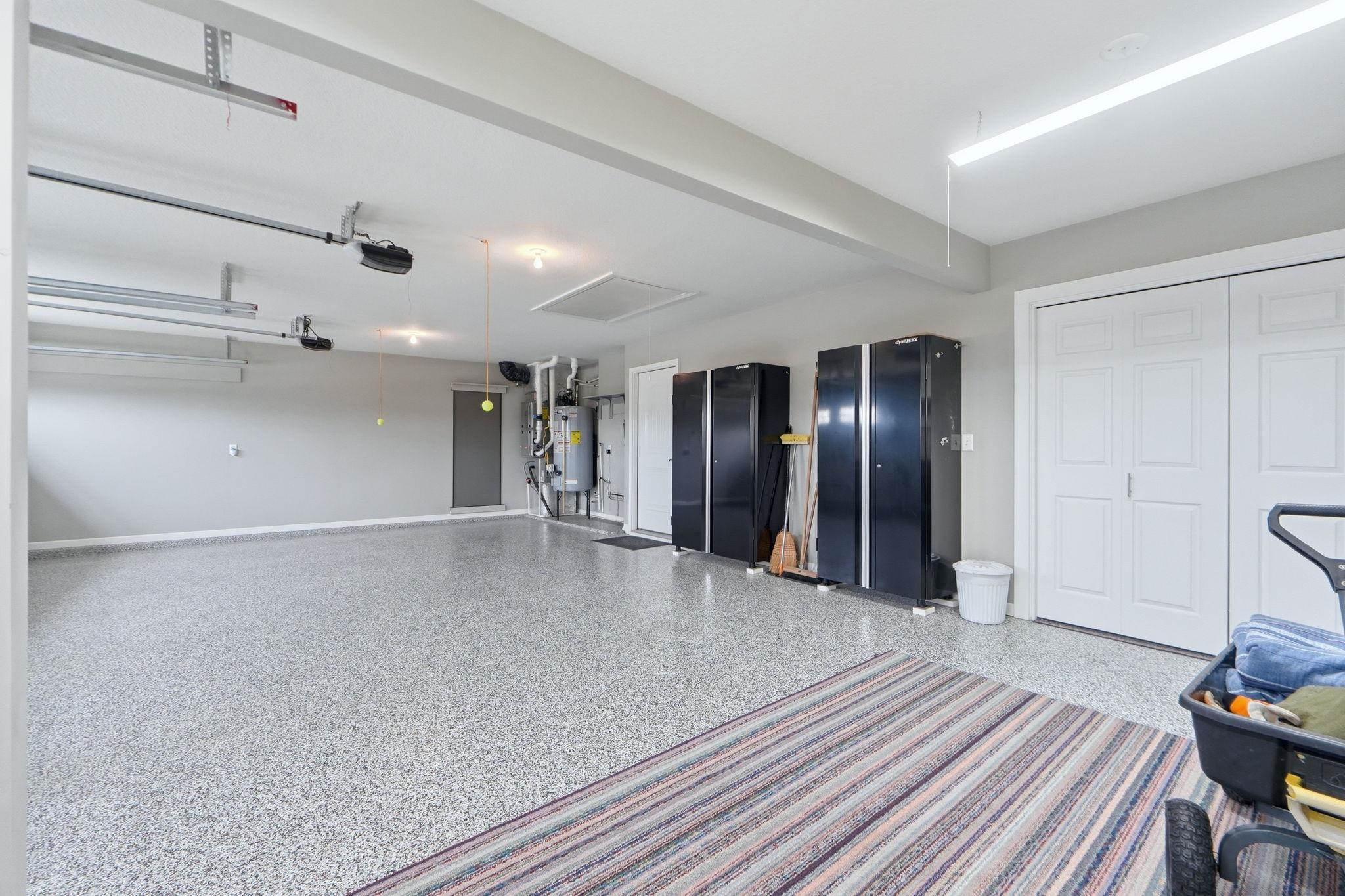 Garage featuring gas water heater and baseboards