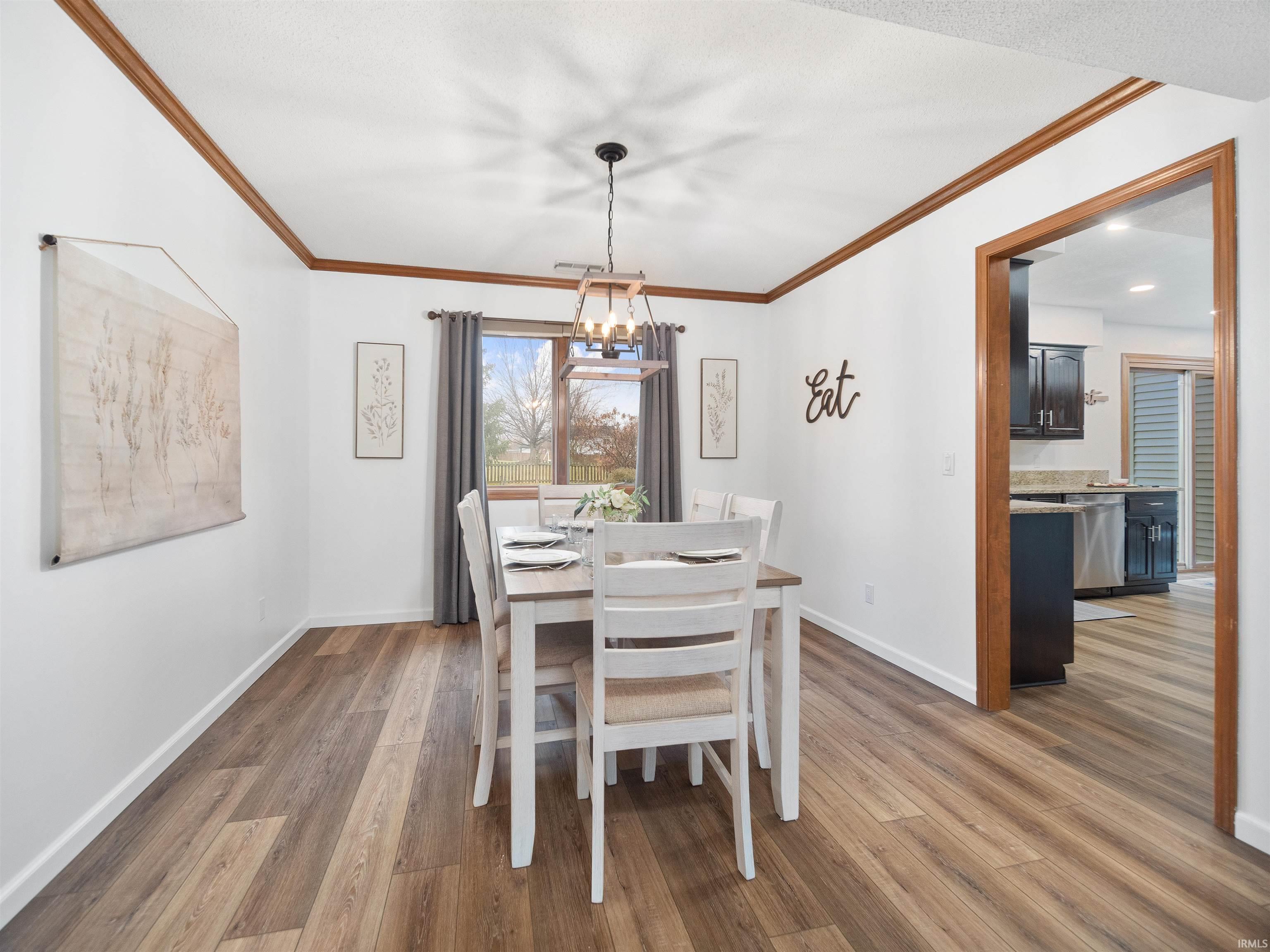 Dining room featuring dark wood-type flooring, crown molding, and hanging lights