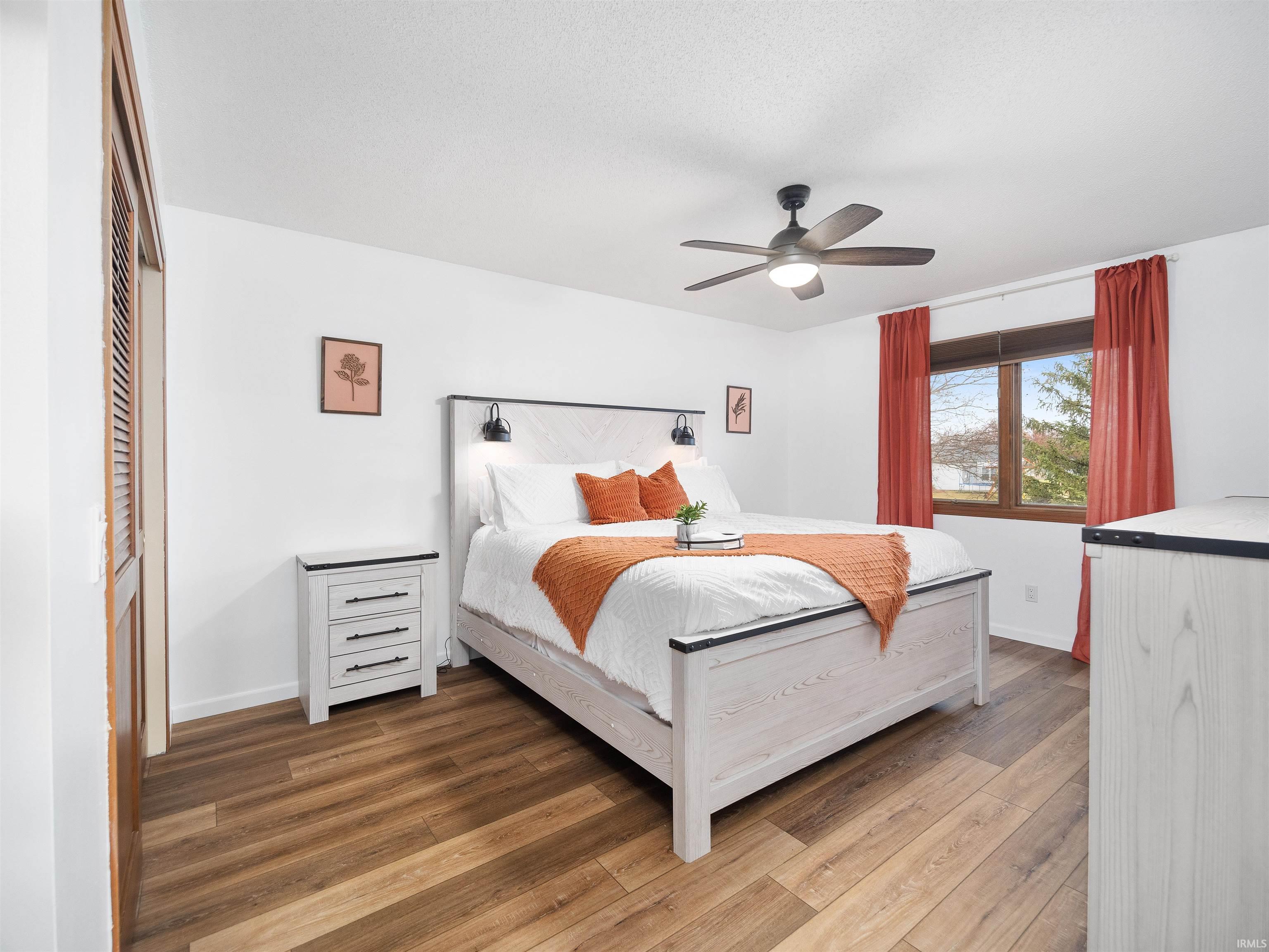 Bedroom with hardwood / wood-style floors, a ceiling fan, and a closet