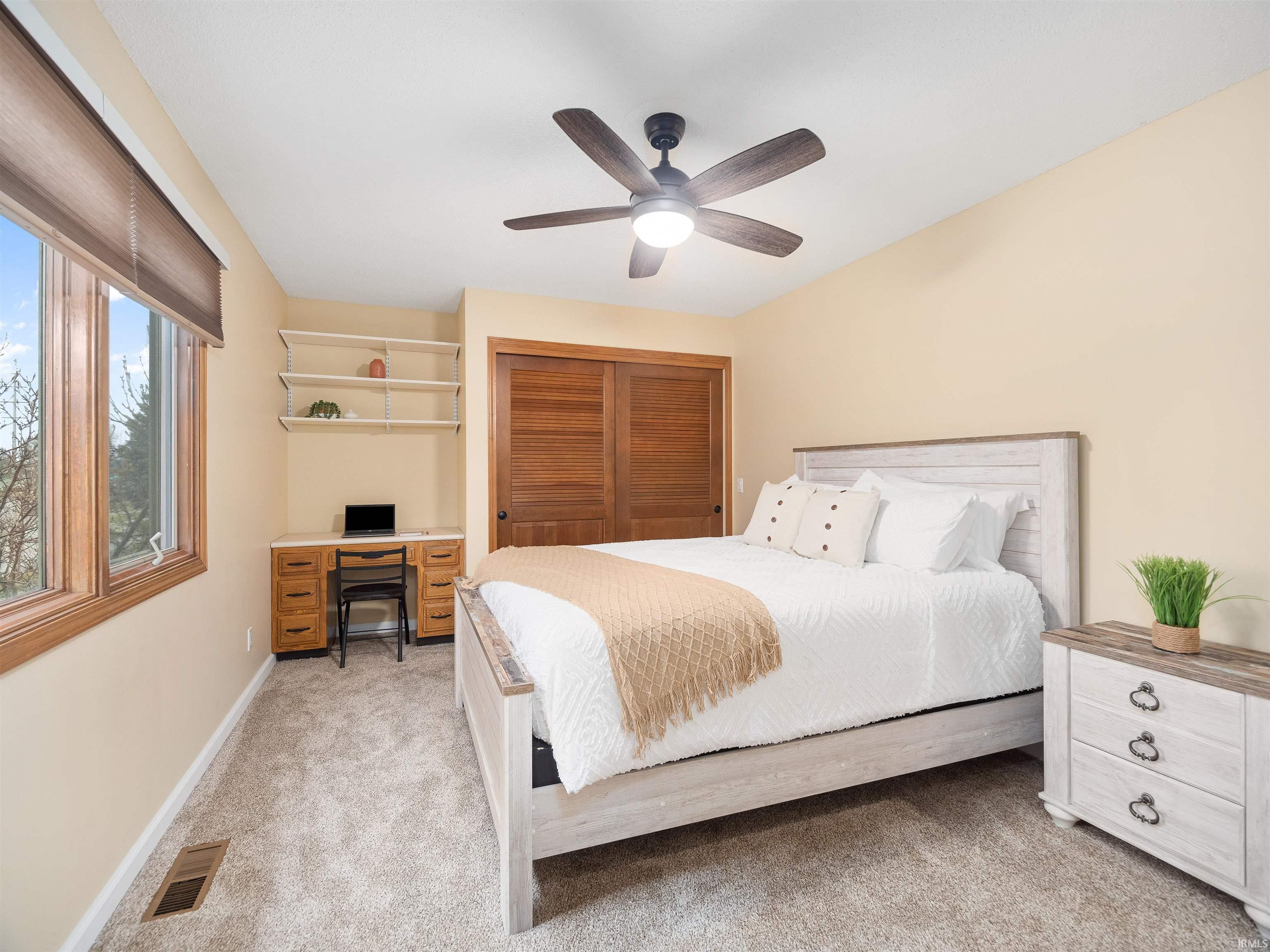Bedroom with a desk, light carpet, ceiling fan, and a closet