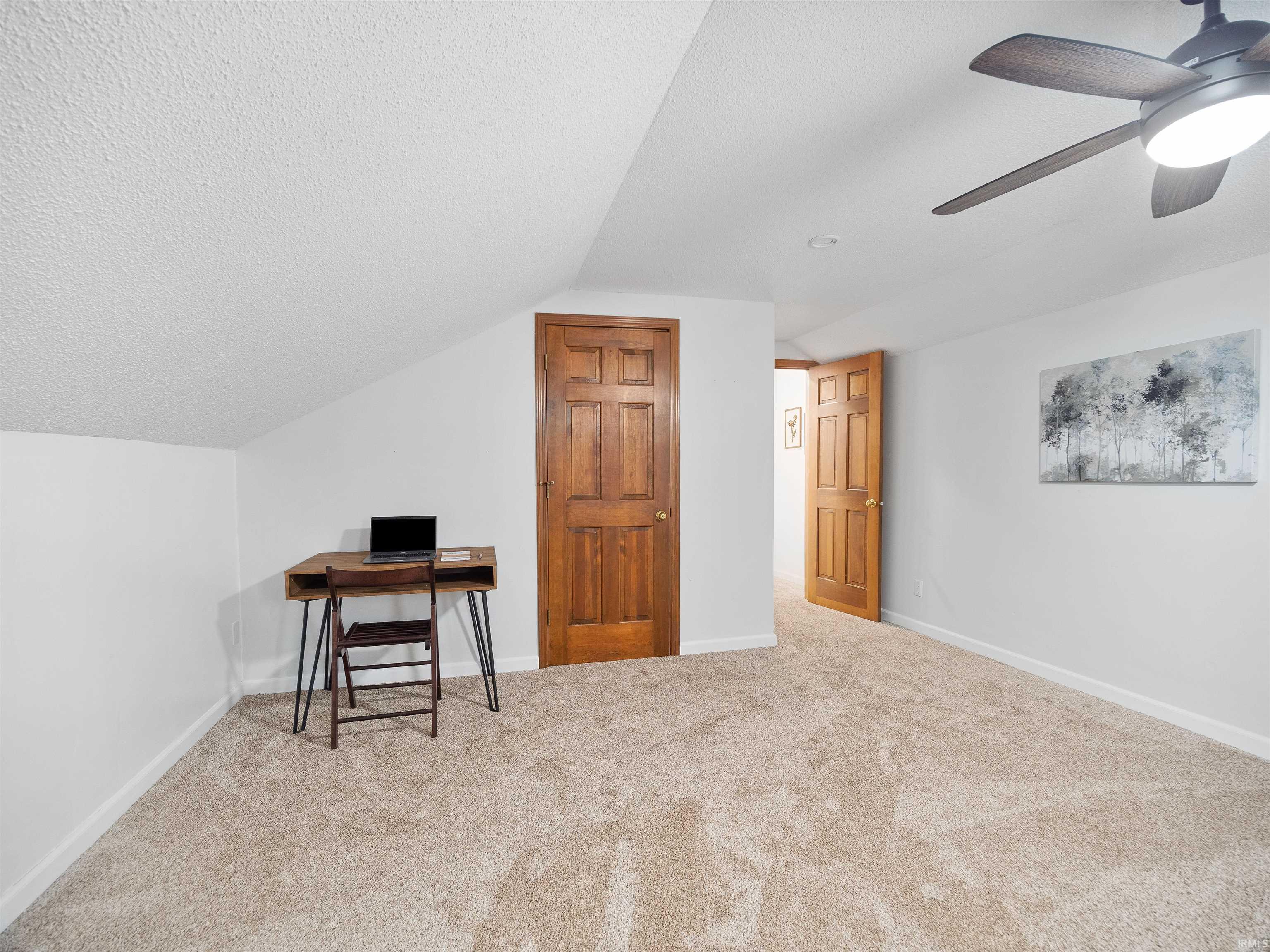Carpeted bedroom with an office area and ceiling fan