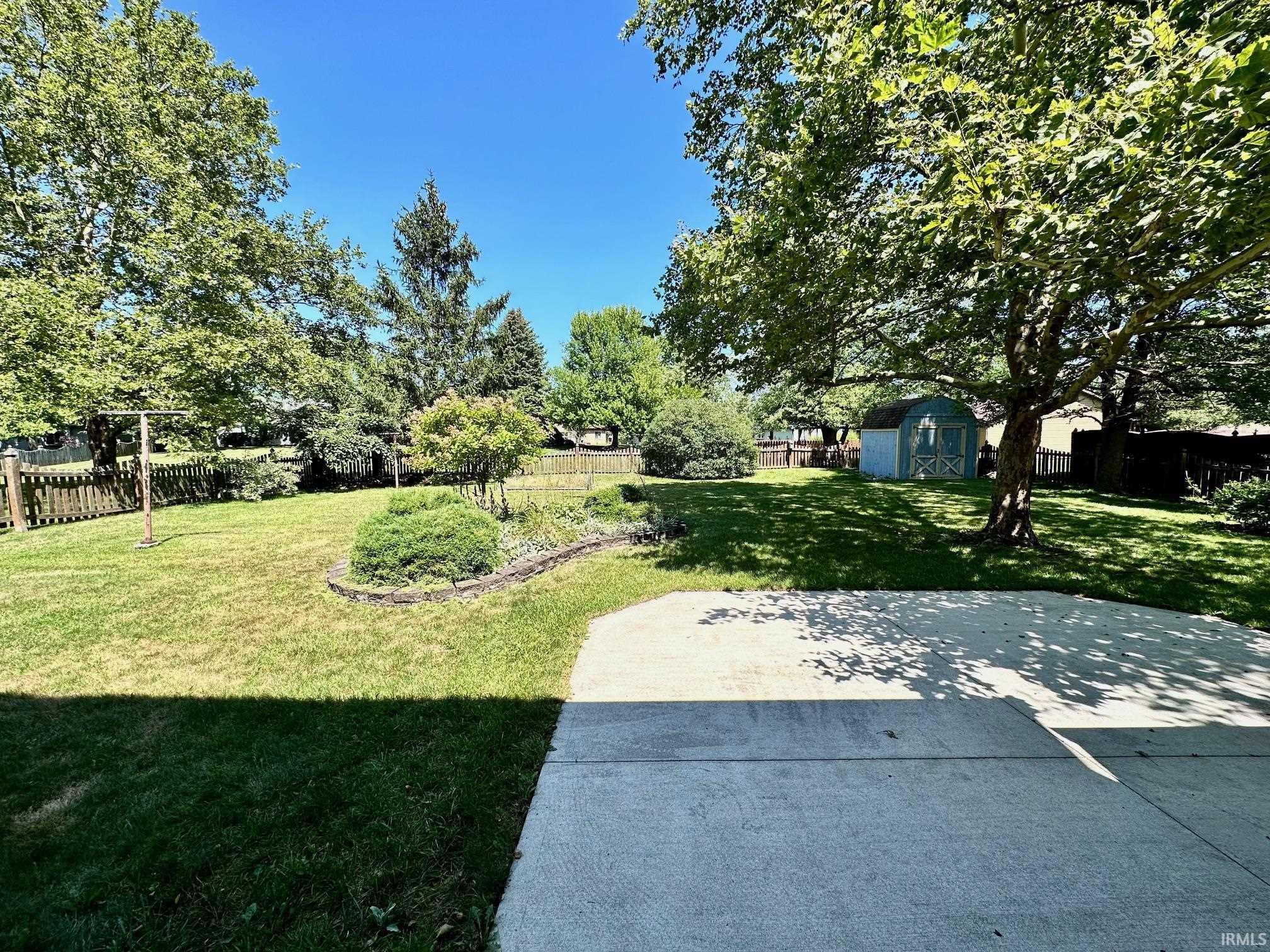 Fenced backyard featuring a storage shed