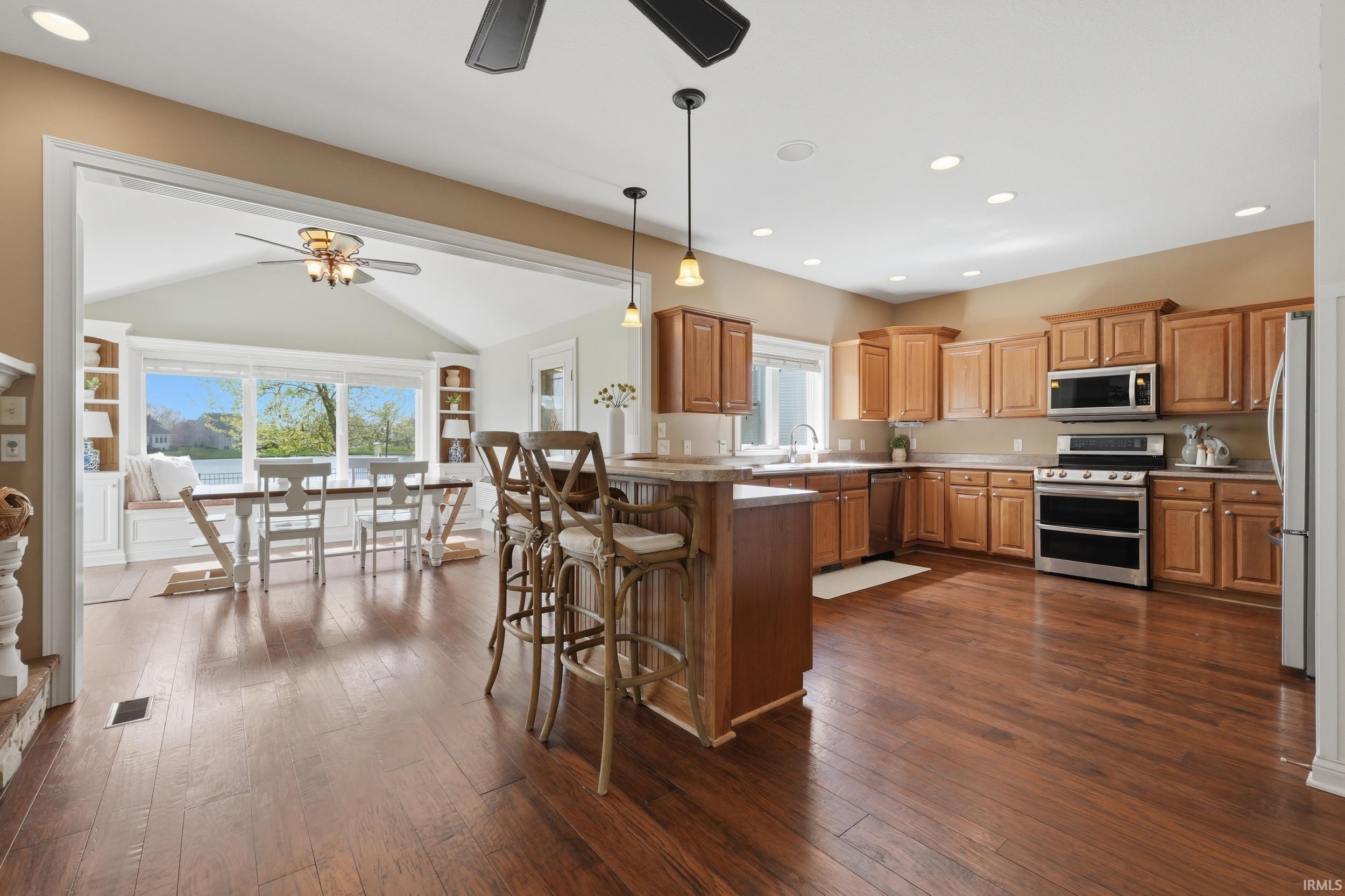 Kitchen featuring a breakfast bar area, stainless steel appliances, a ceiling fan, a peninsula, and lofted ceiling