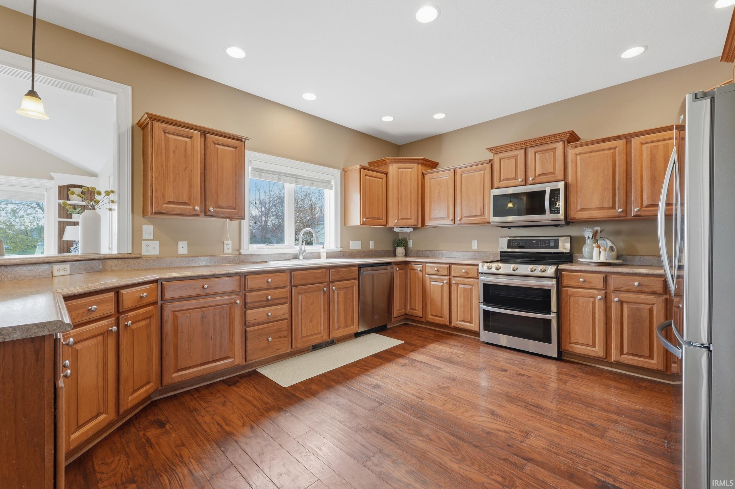 Kitchen with stainless steel appliances, dark wood finished floors, wood finish cabinets, and light countertops