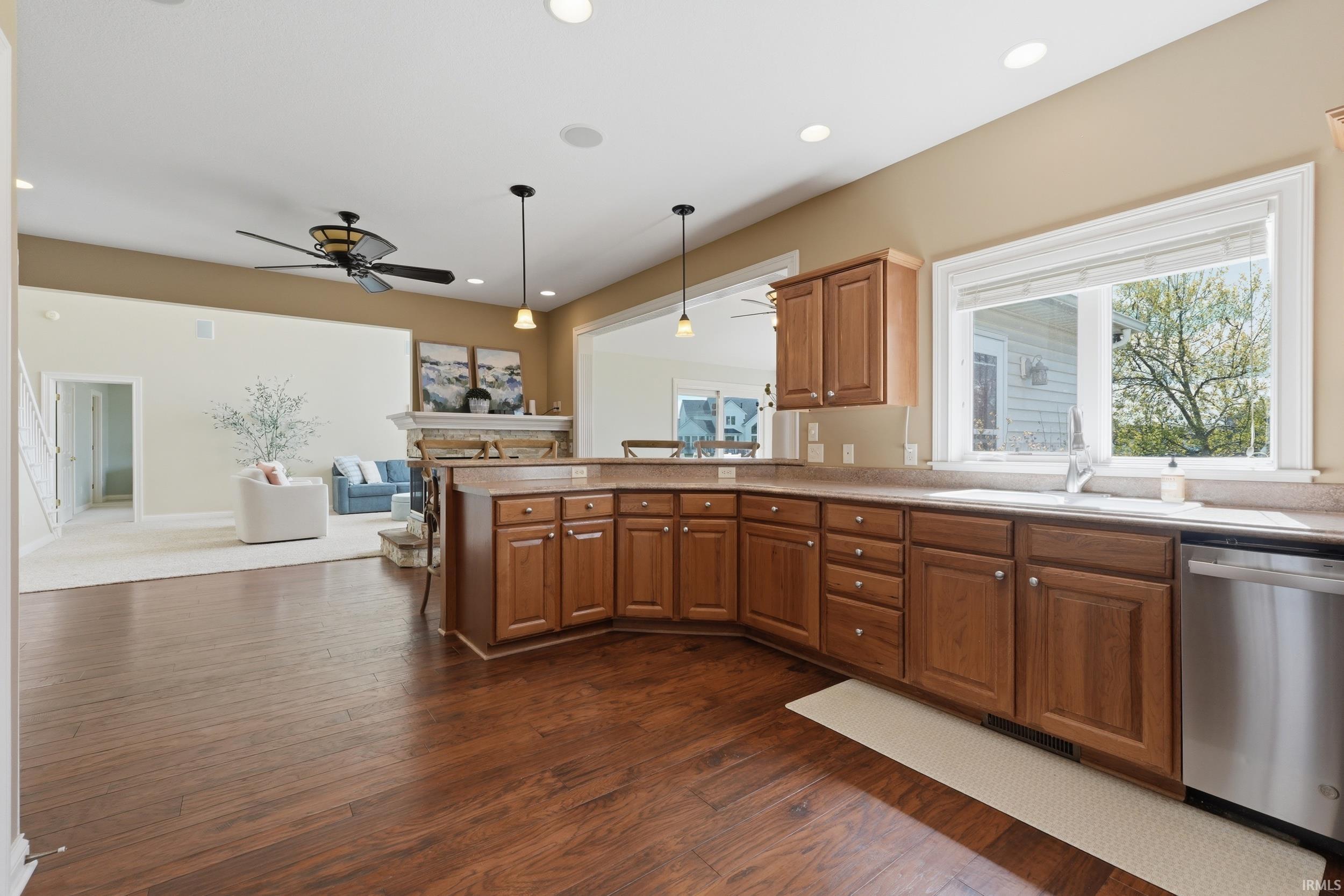 Kitchen with dishwasher, a ceiling fan, a peninsula, hanging light fixtures, and light countertops