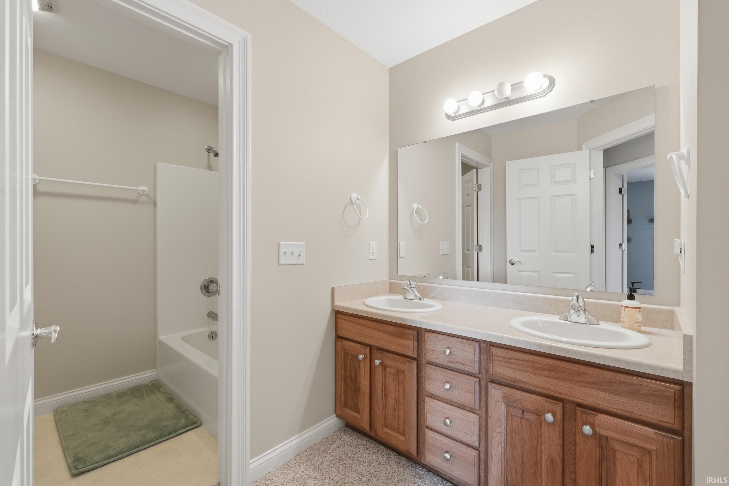 Full bath featuring double vanity and washtub / shower combination
