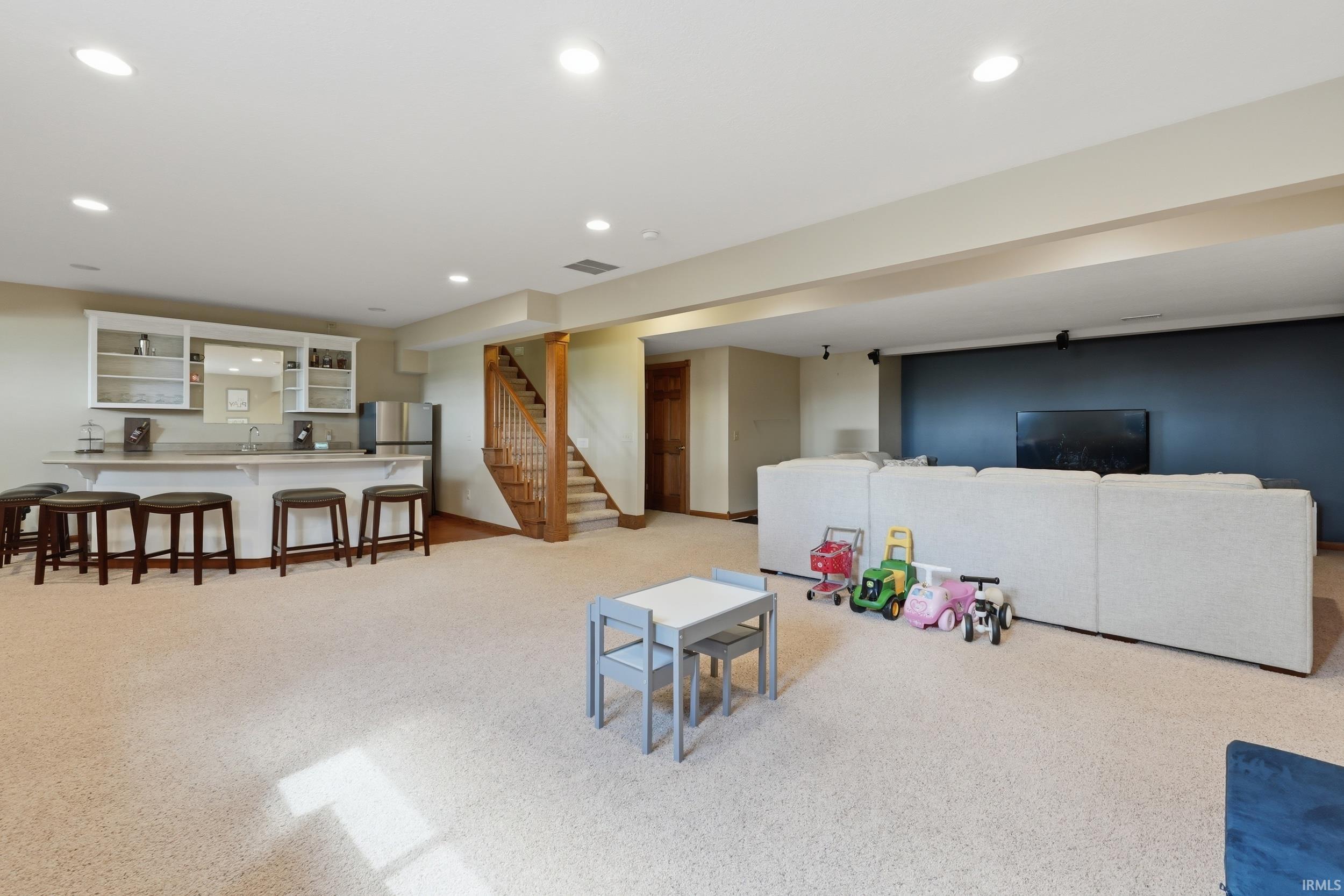 Living area with light carpet, recessed lighting, and wet bar