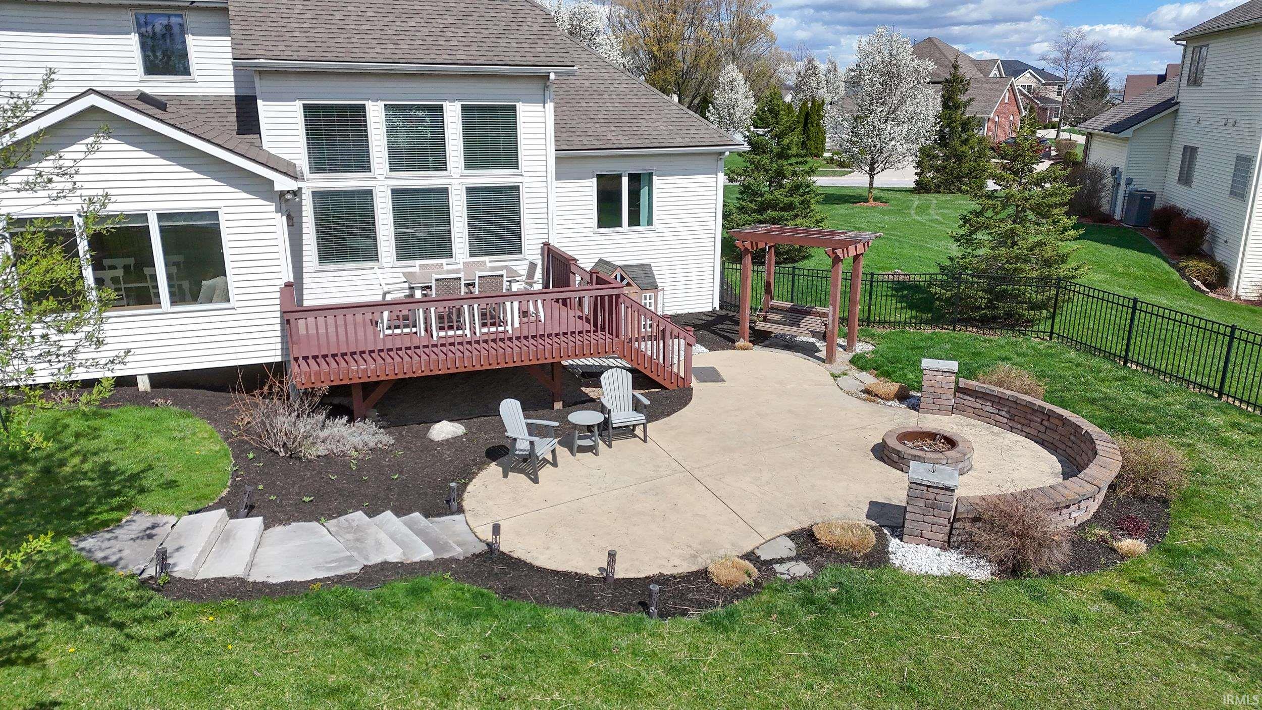Back of property featuring a patio, roof with shingles, a fire pit, and a deck