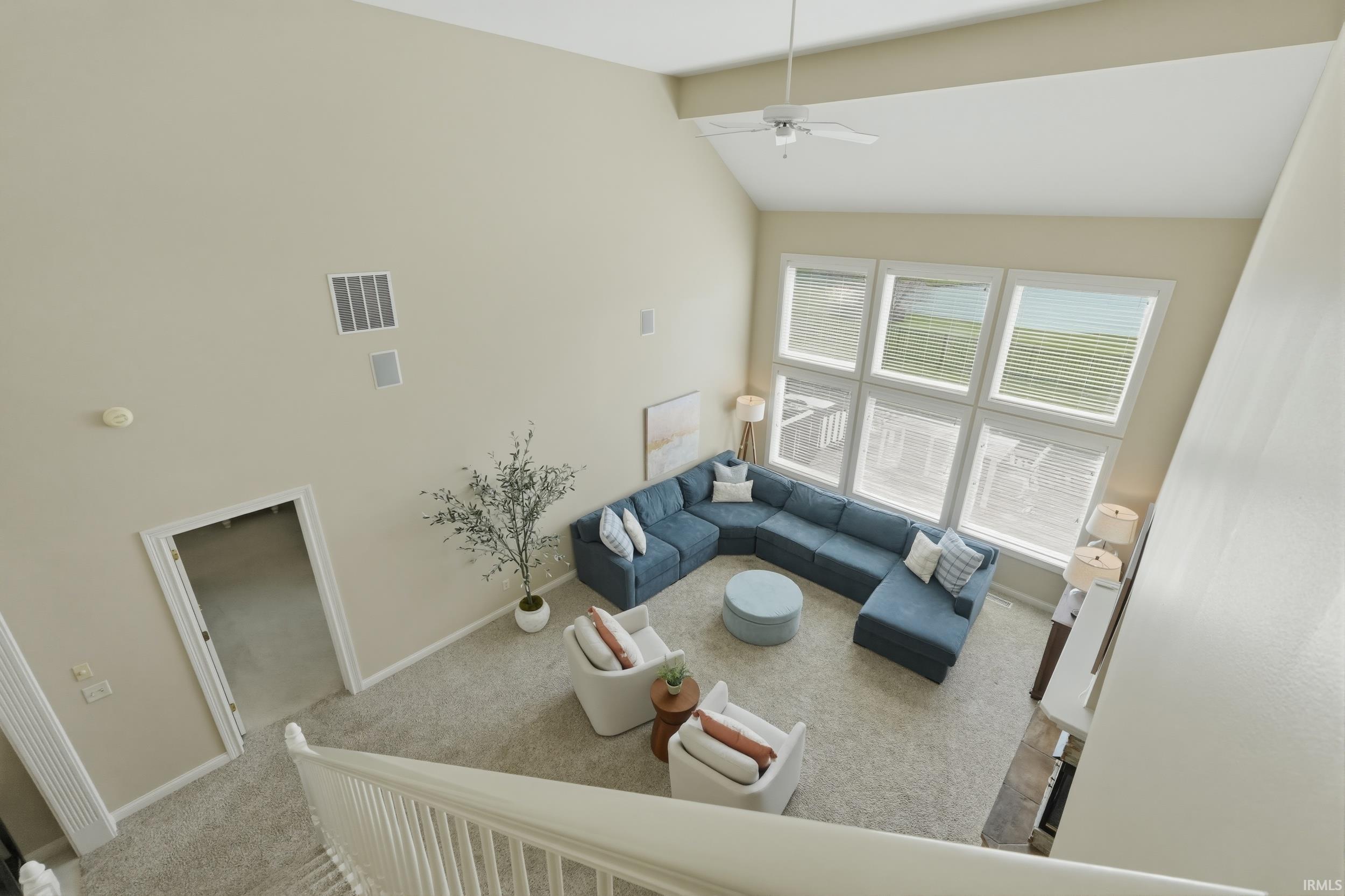 Living area featuring vaulted ceiling, light colored carpet, and a ceiling fan