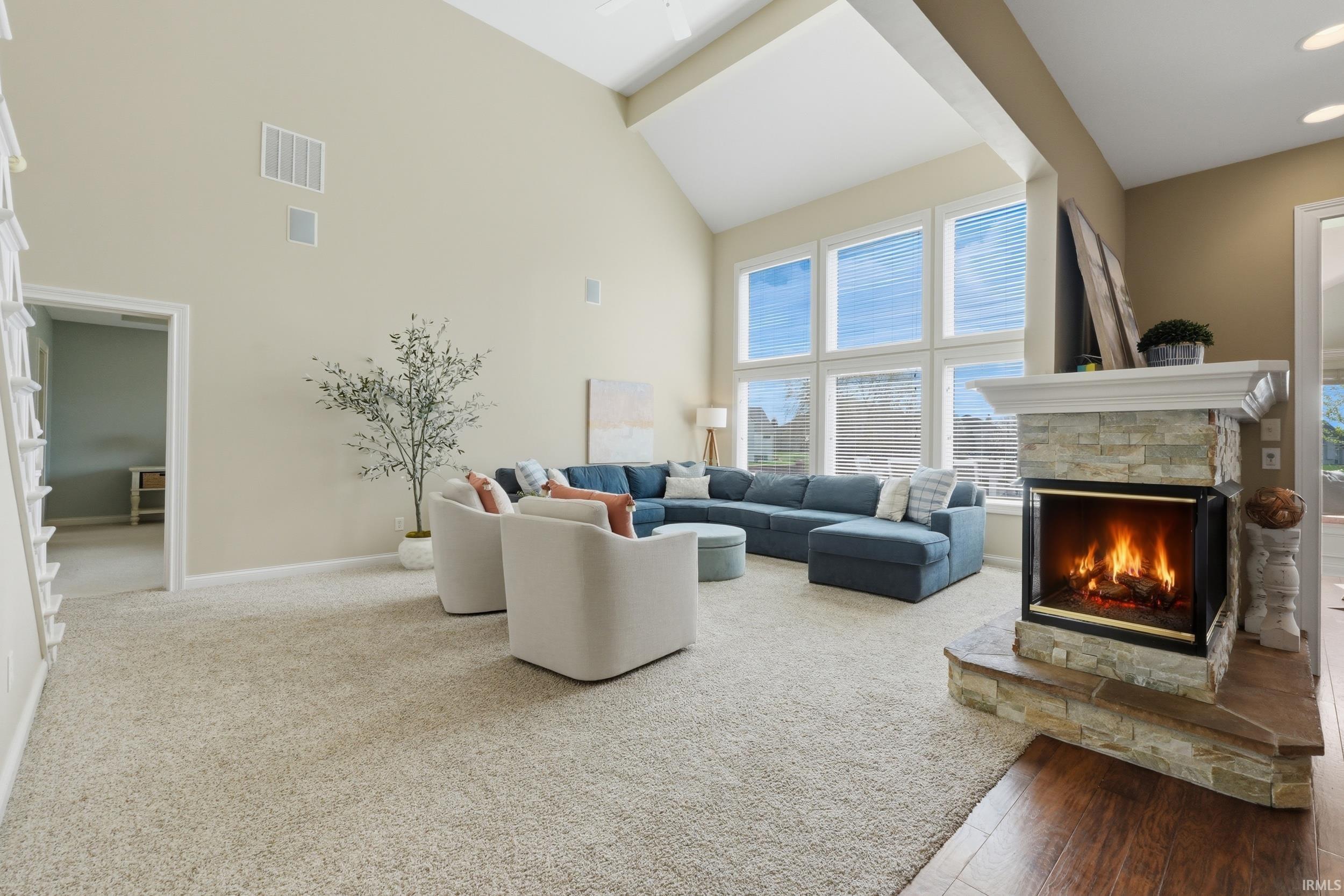 Living room featuring light carpet, a fireplace, and vaulted ceiling