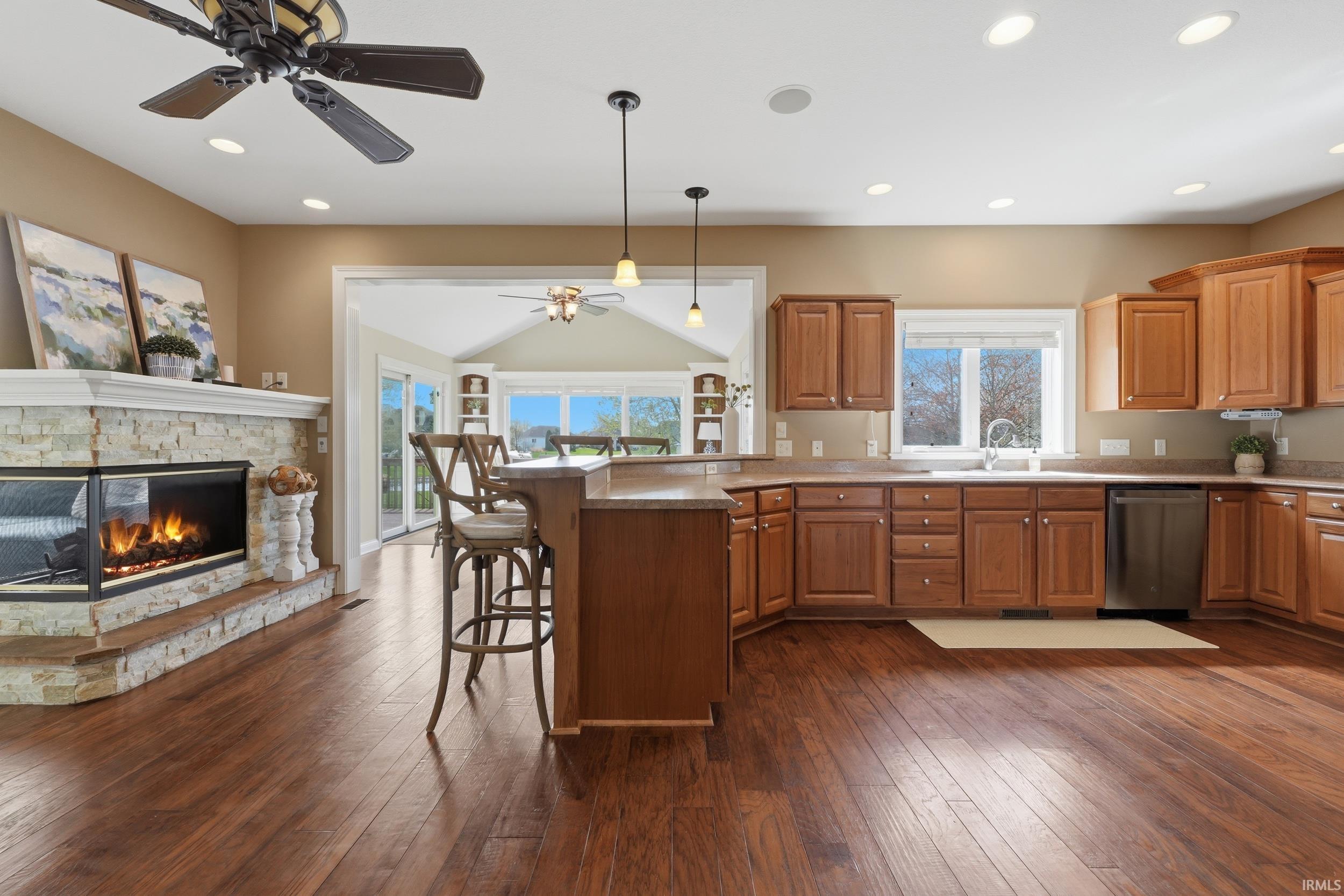 Kitchen featuring a peninsula, a kitchen bar, a ceiling fan, wood finish cabinets, and dishwasher