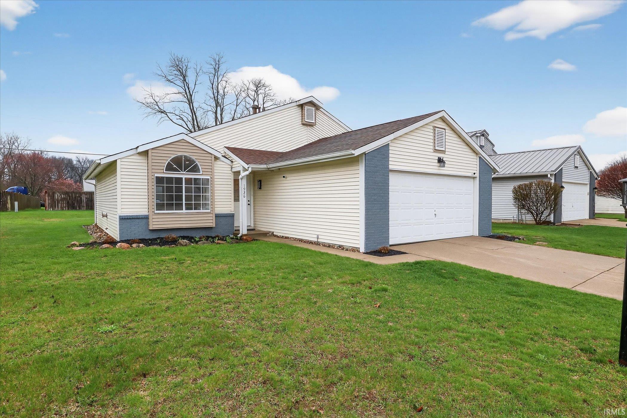 View of front of house featuring a front lawn, an attached garage, and driveway