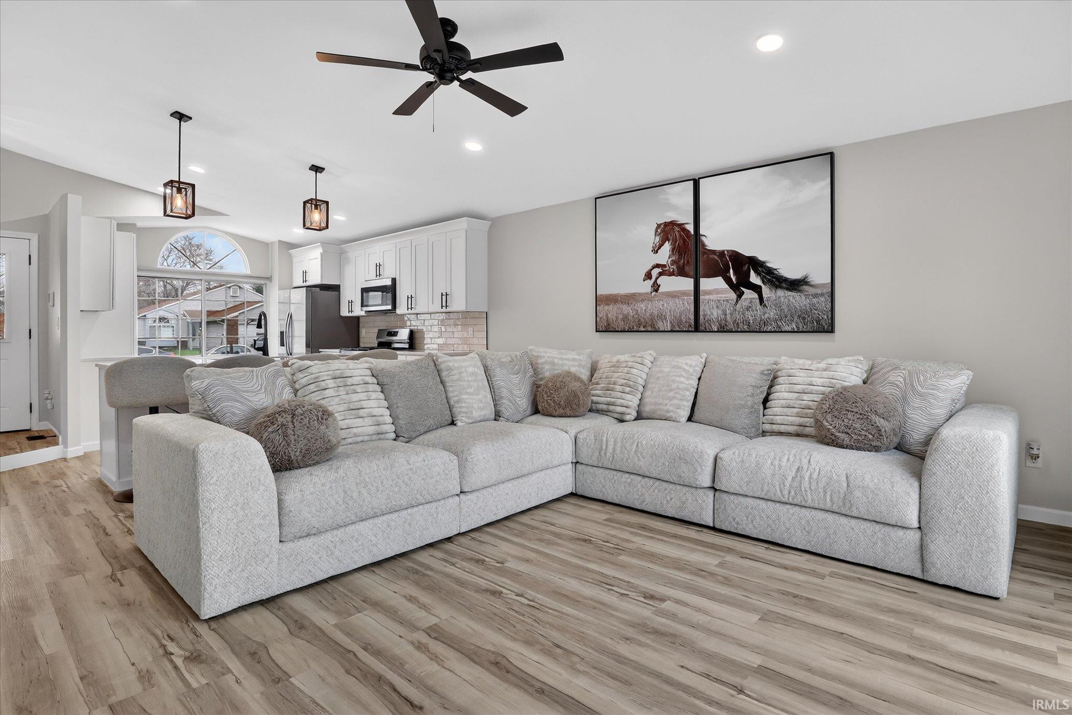 Living room featuring a ceiling fan, light wood-style flooring, recessed lighting, and lofted ceiling