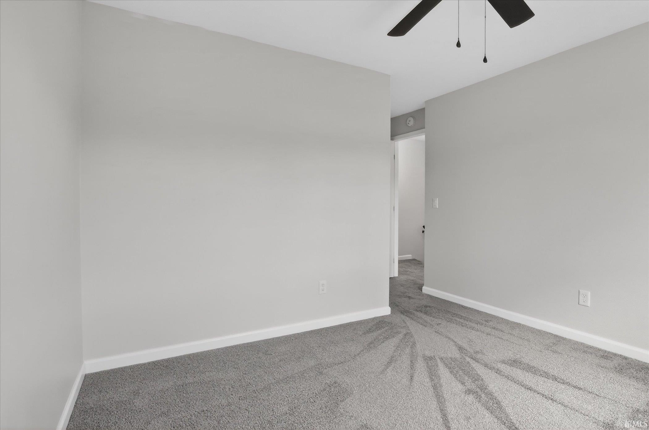Spare room featuring light colored carpet and a ceiling fan