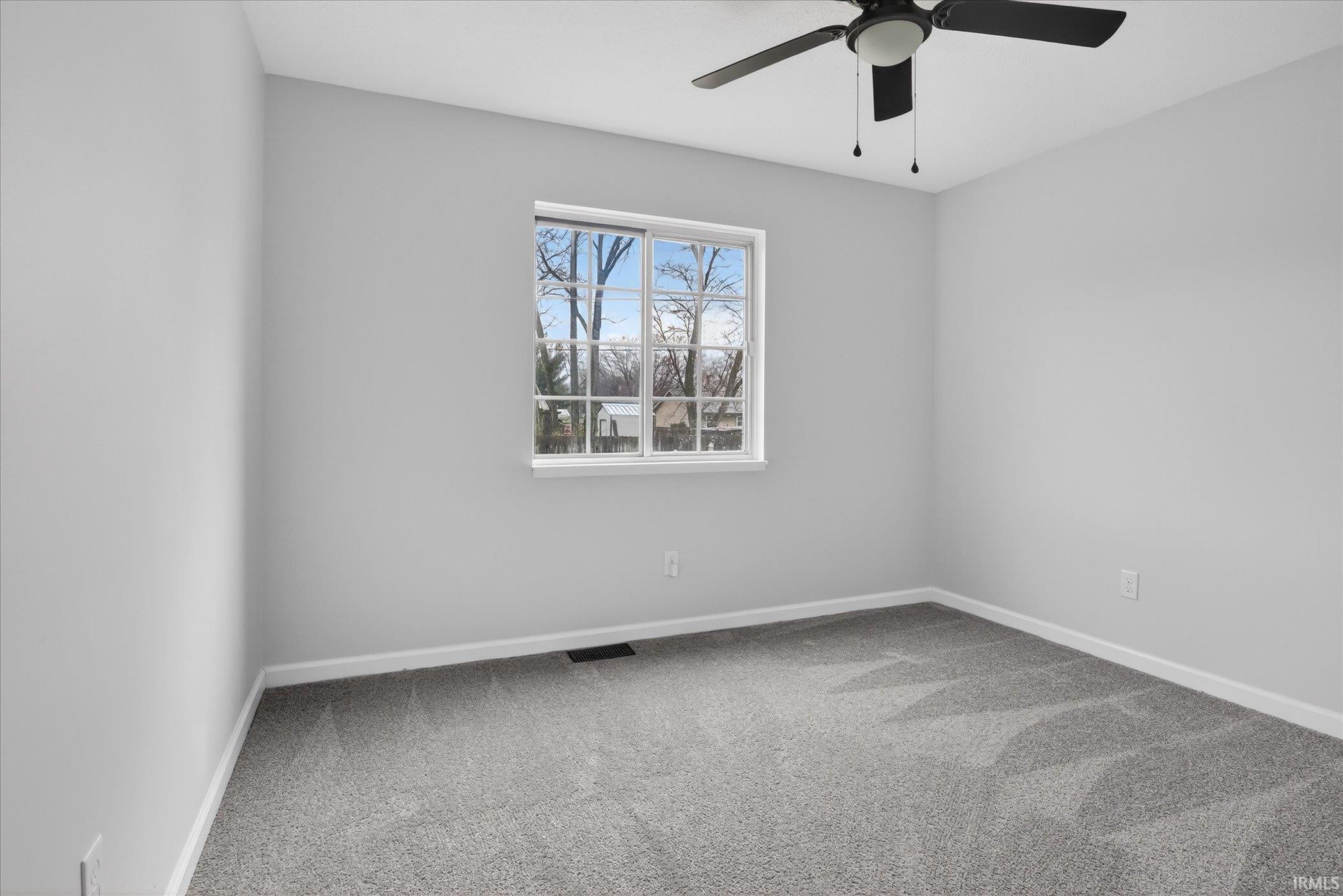 Unfurnished room featuring light carpet and a ceiling fan