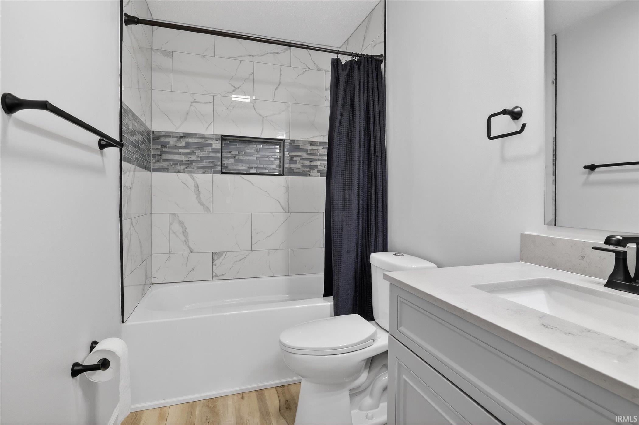 Bathroom featuring vanity, light wood finished floors, and shower / tub combo with curtain