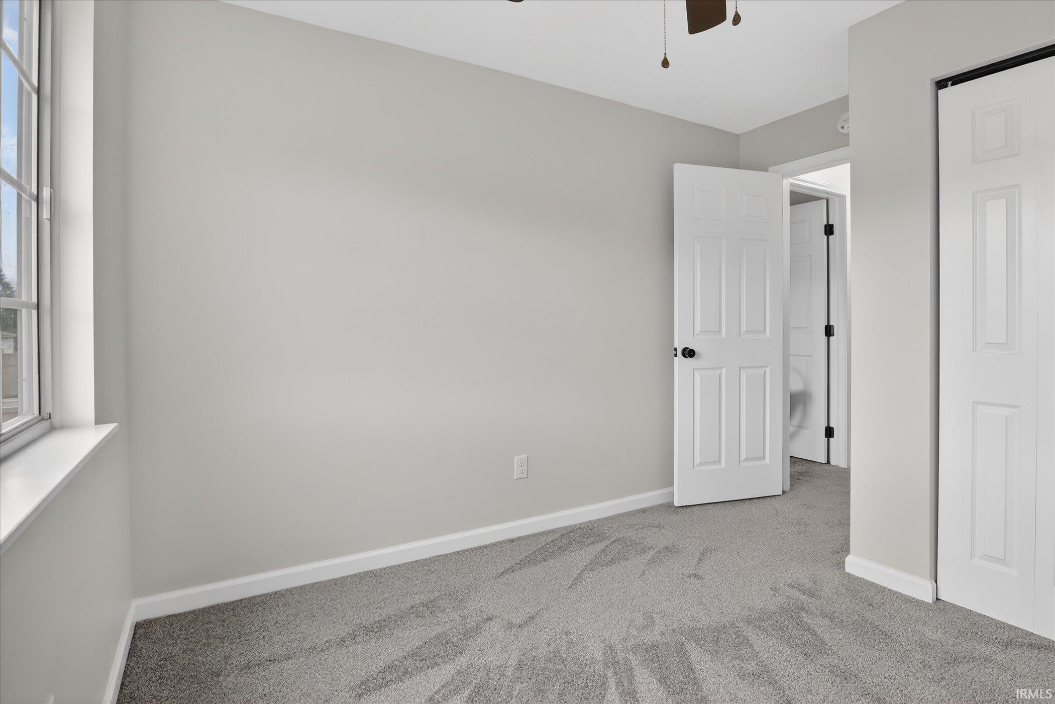 Unfurnished bedroom with light colored carpet and ceiling fan