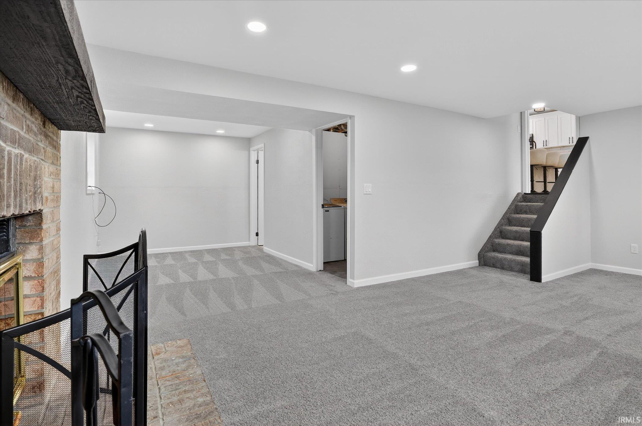 Finished below grade area with light colored carpet, a fireplace, recessed lighting, and washer / clothes dryer