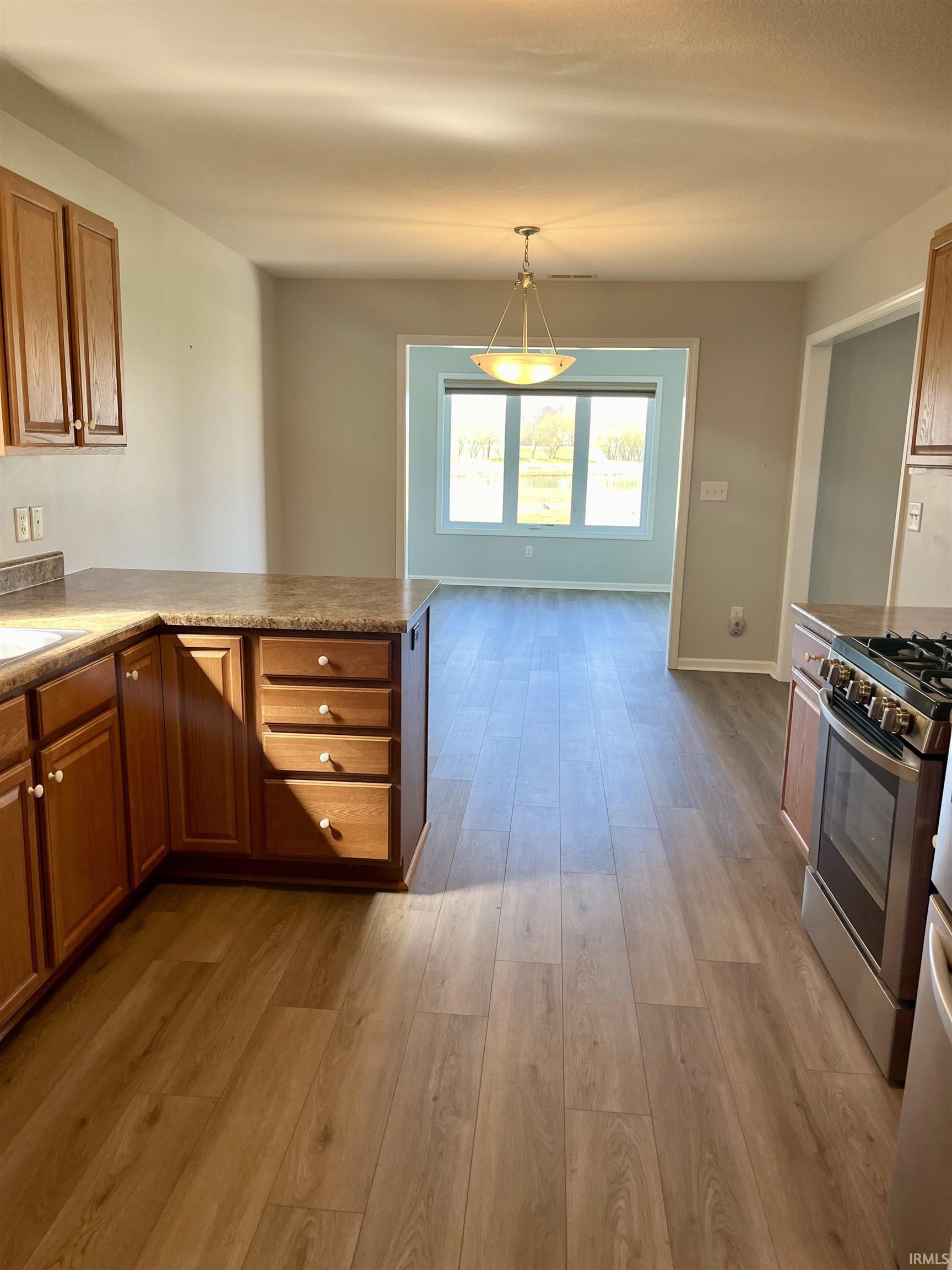 Kitchen featuring wood finish cabinetry, stainless steel appliances, and light wood-type flooring