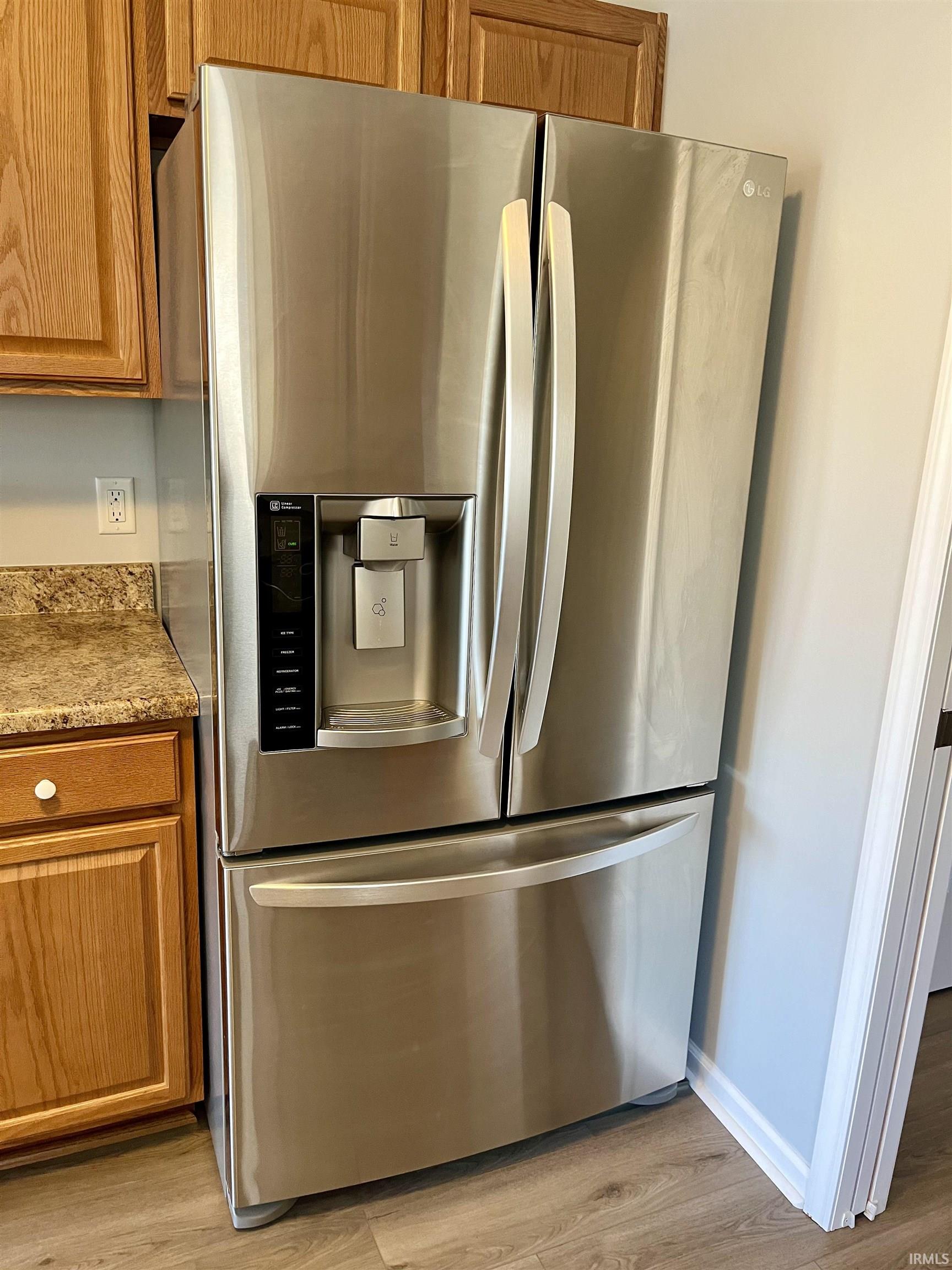 Kitchen with stainless steel fridge, wood finish cabinetry, and light wood finished floors