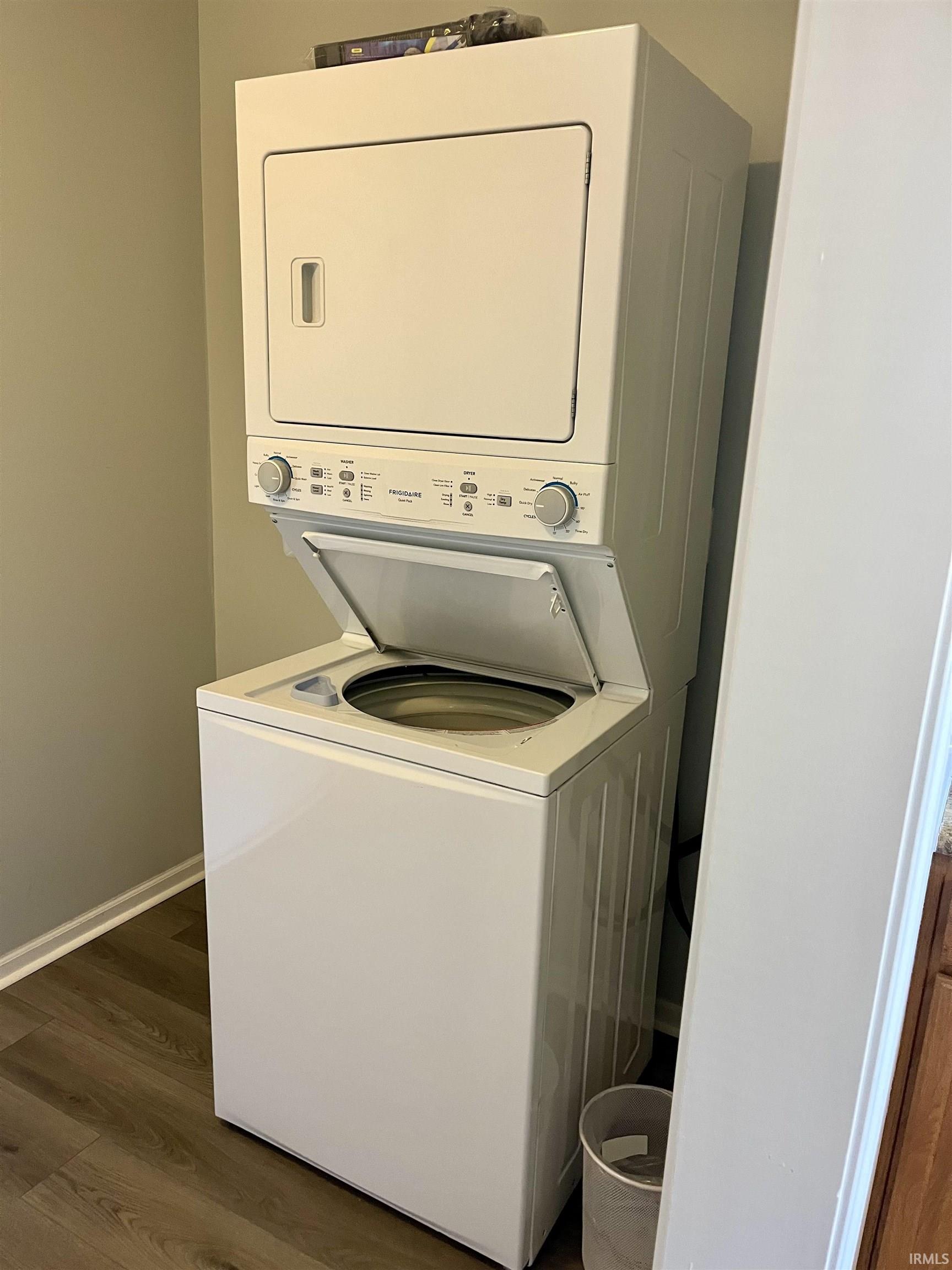 Laundry area featuring dark wood finished floors and stacked washer / drying machine