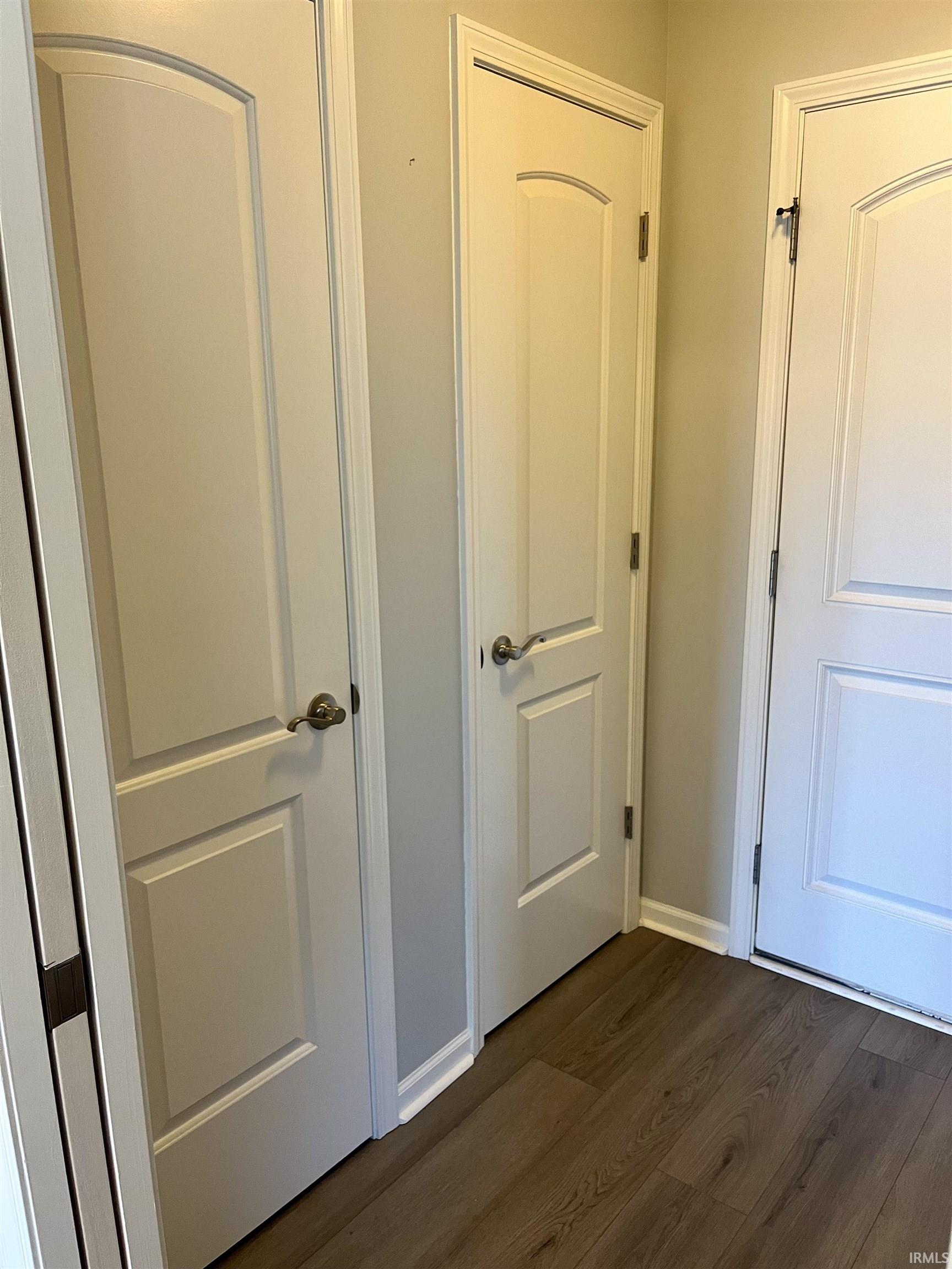 Hallway with dark wood-type flooring and baseboards