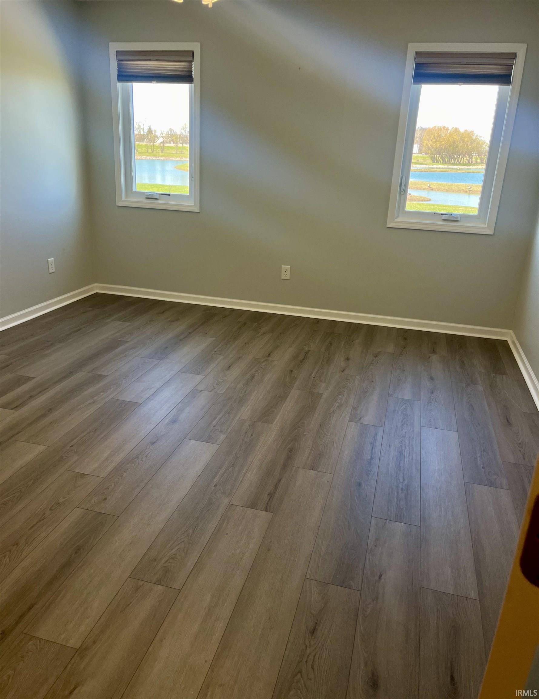 Unfurnished room featuring dark wood-style flooring and a water view