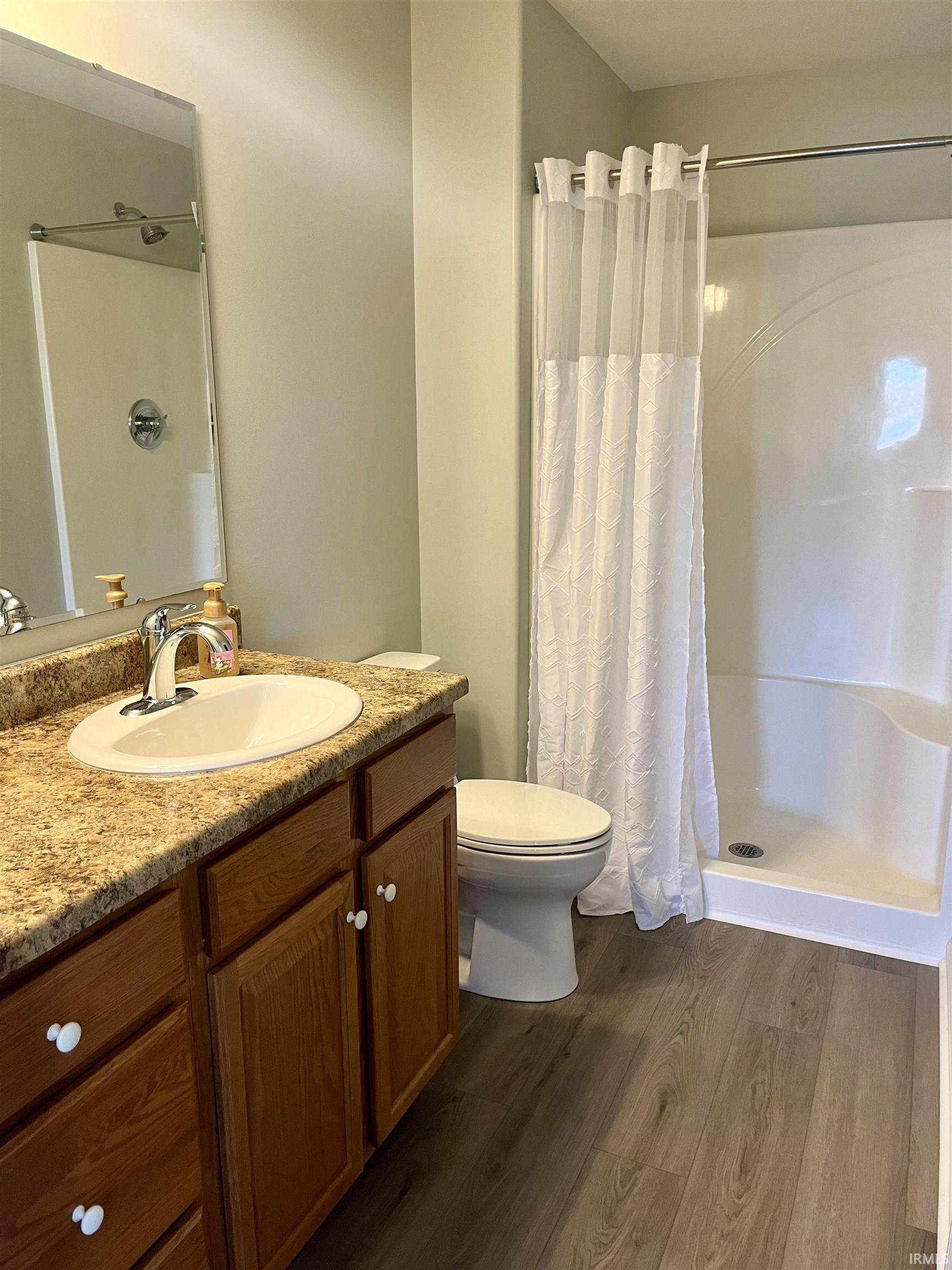 Full bath featuring a shower stall, dark wood-type flooring, and vanity