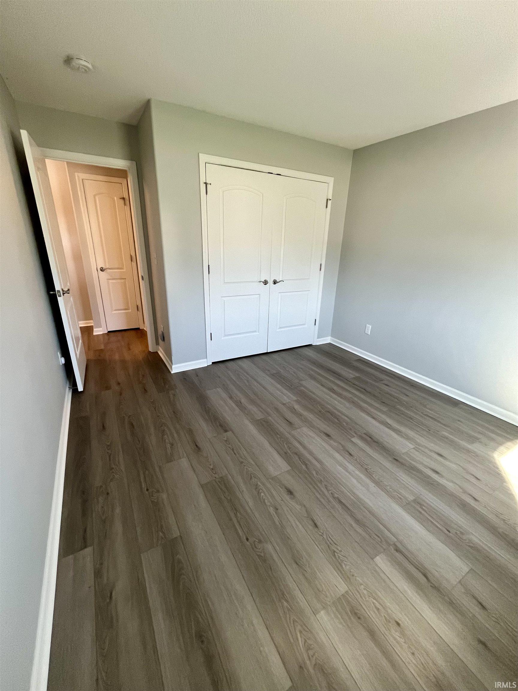 Unfurnished bedroom with dark wood finished floors and a closet