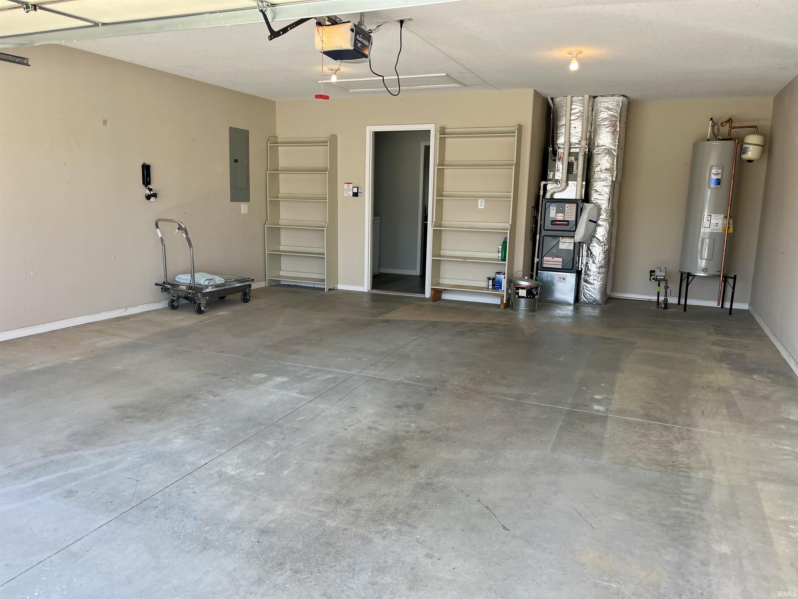 Garage featuring water heater, electric panel, heating unit, and a garage door opener