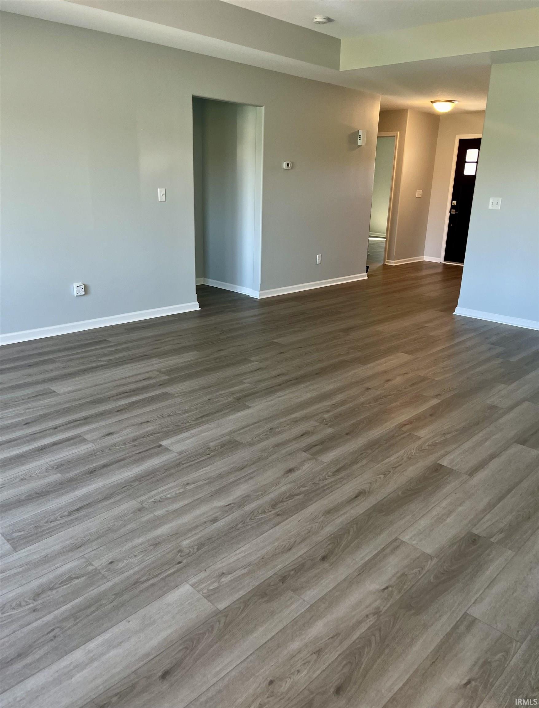 Spare room featuring baseboards and dark wood-style floors