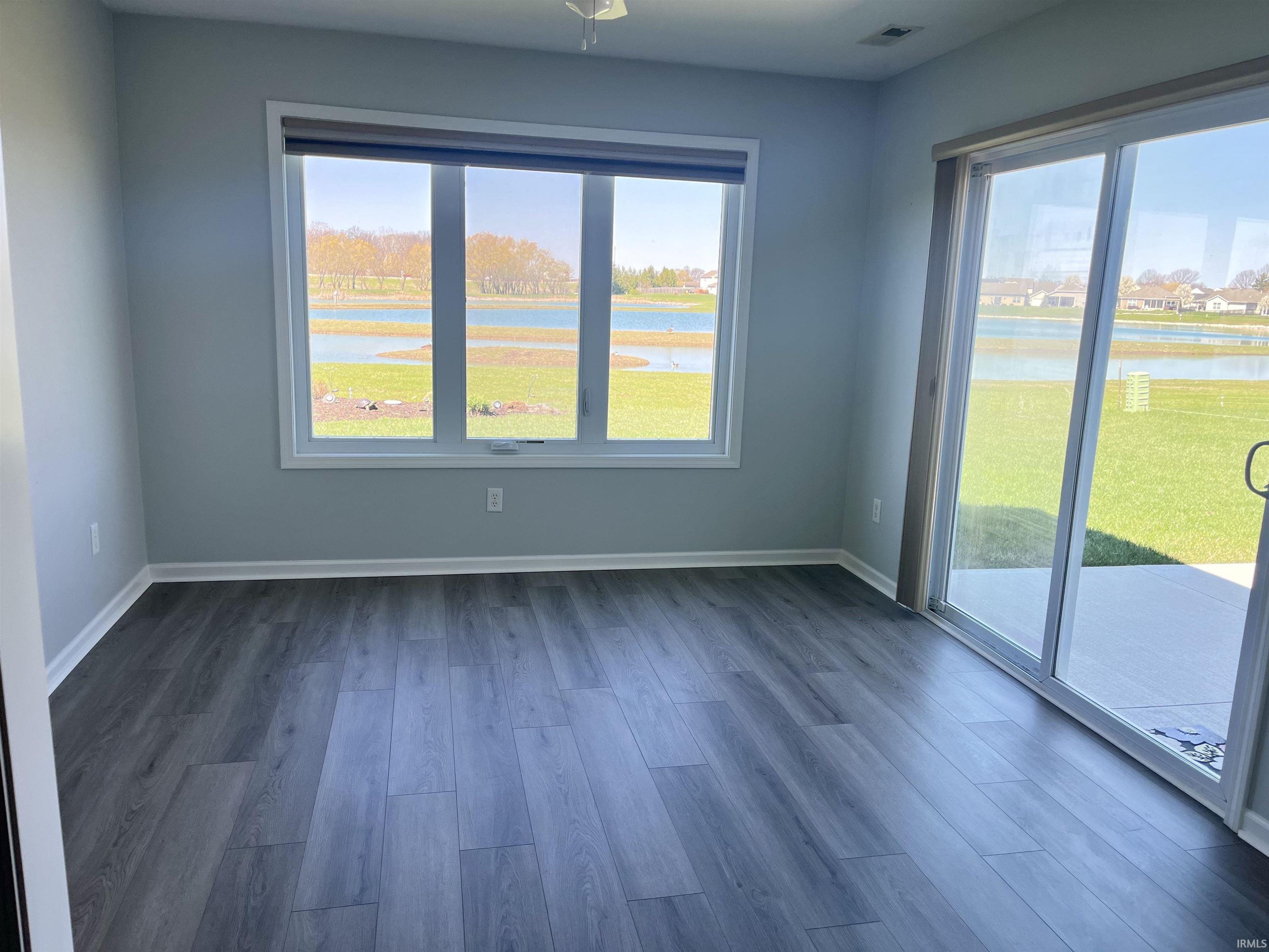 Unfurnished room with a water view and dark wood-style flooring