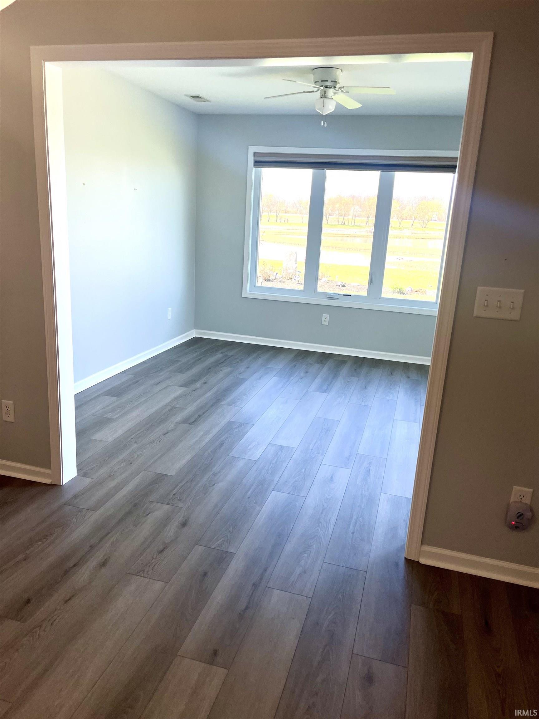 Unfurnished room with ceiling fan and dark wood-style floors