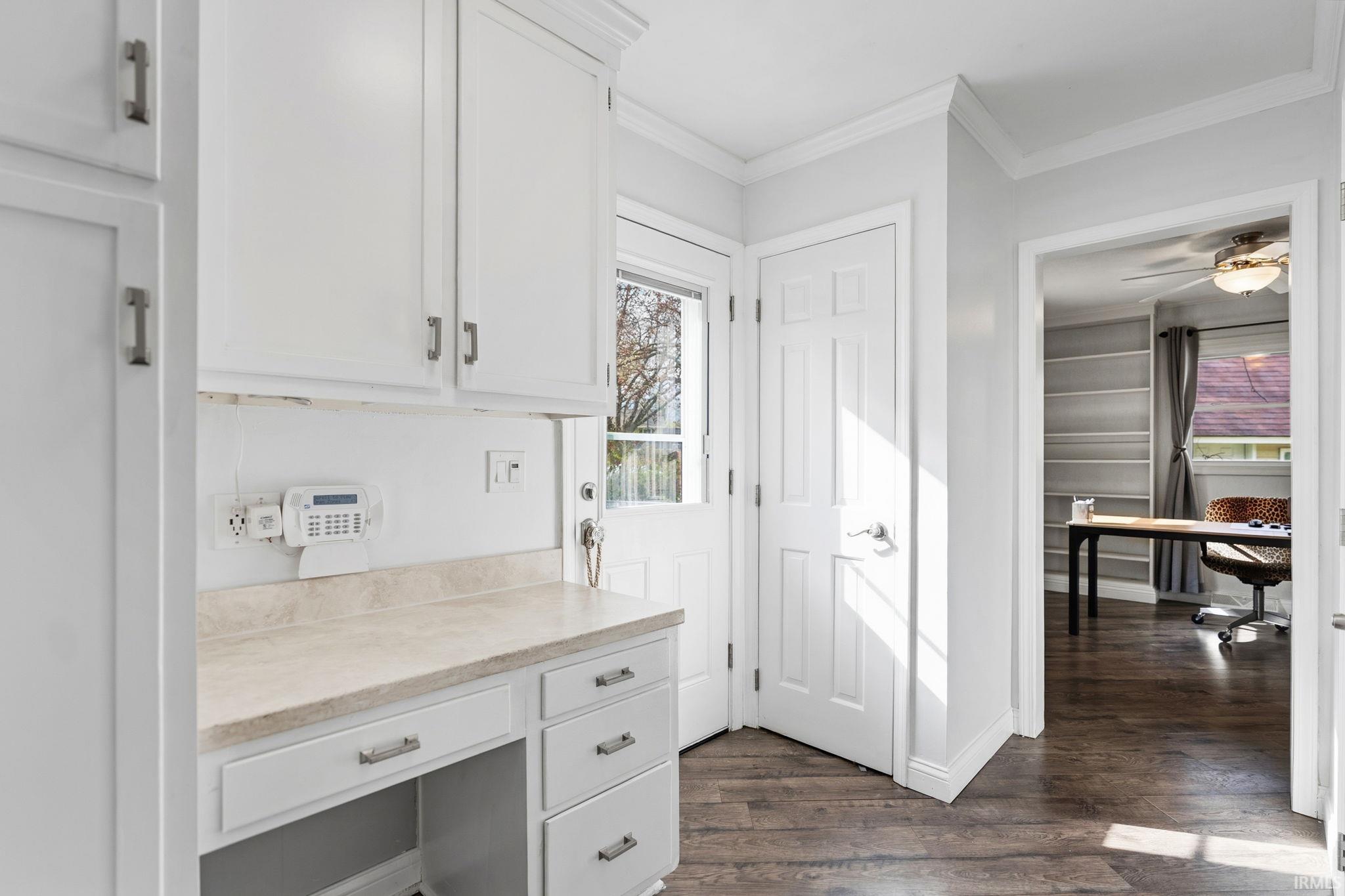 Office area with dark wood-type flooring, crown molding, and a ceiling fan