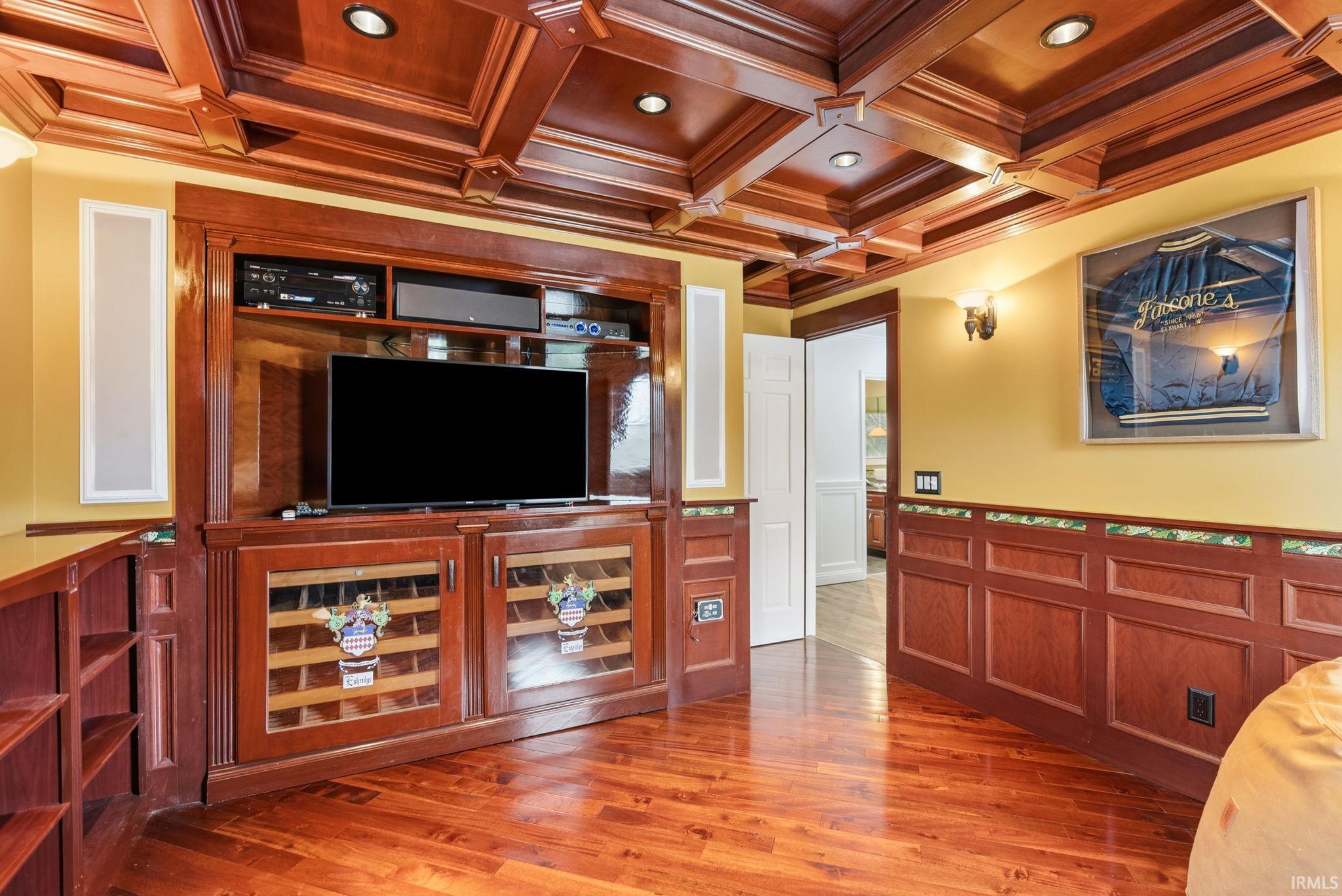 Living area featuring a wainscoted wall, coffered ceiling, light wood-type flooring, a decorative wall, and crown molding