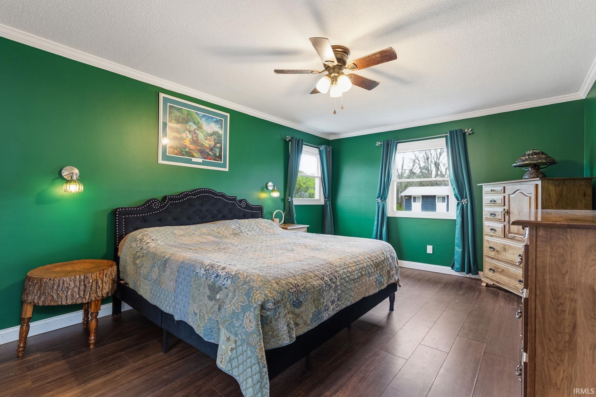 Bedroom featuring dark wood-style flooring, crown molding, a ceiling fan, and a textured ceiling