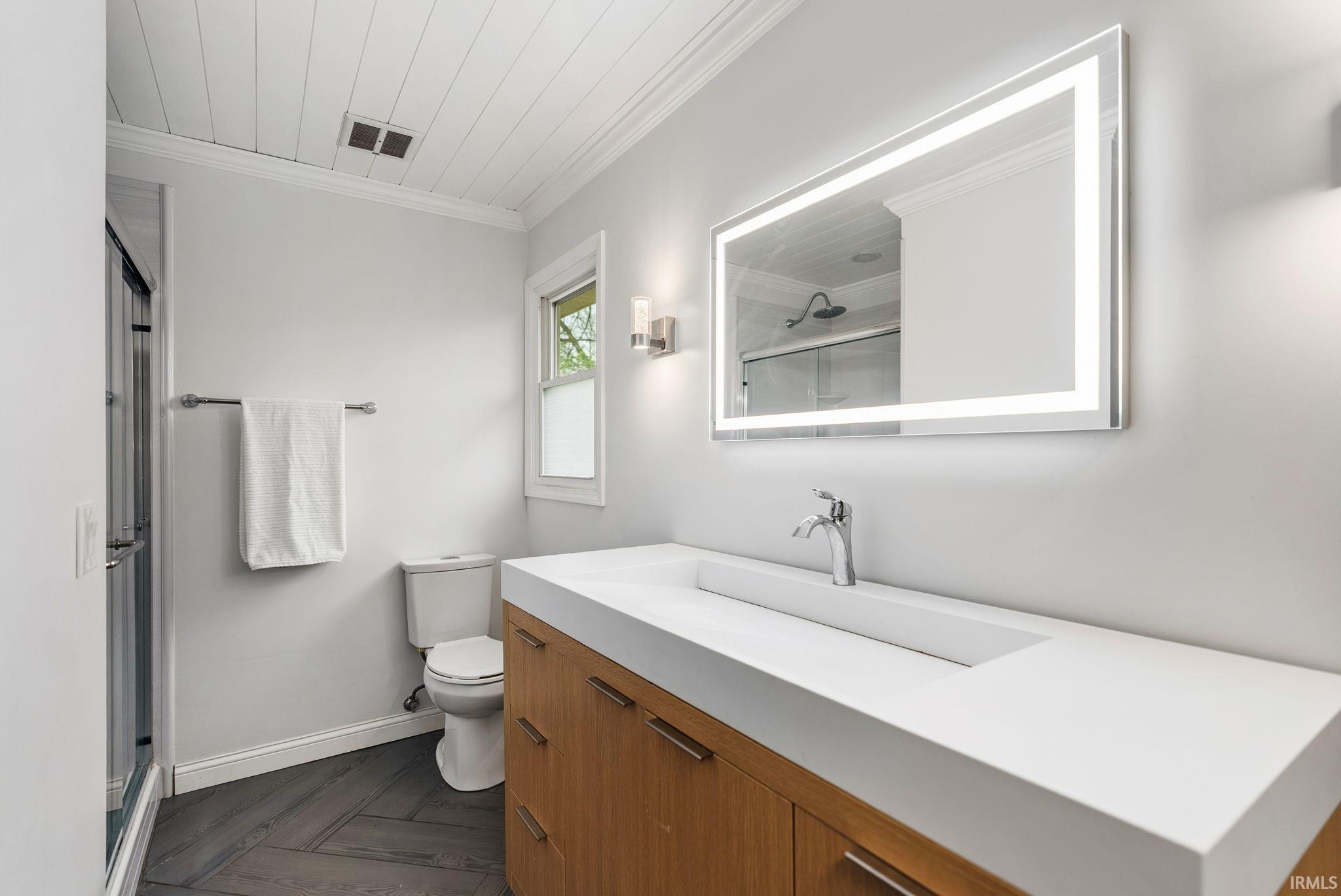 Bathroom featuring a stall shower, crown molding, vanity, and parquet floors