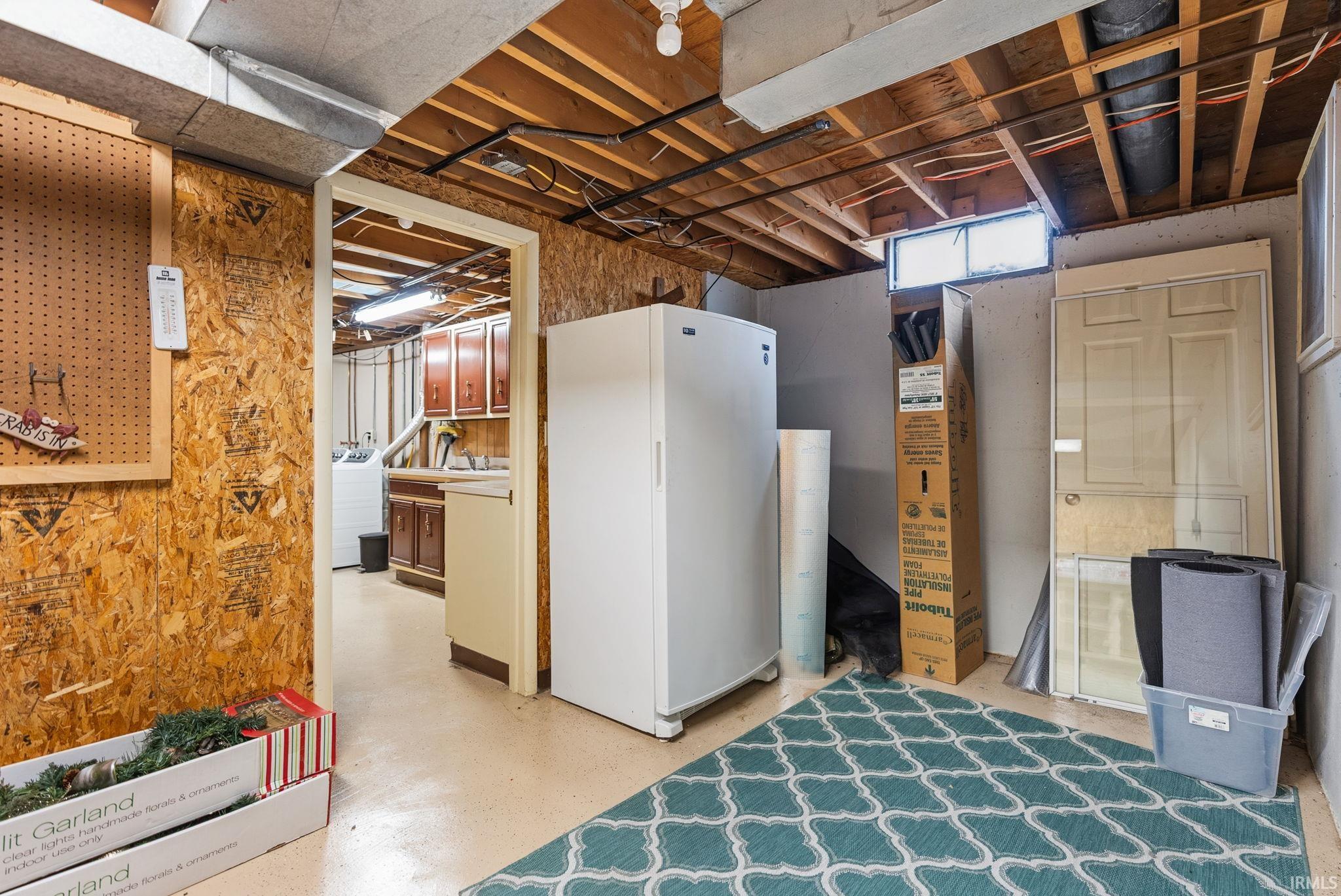 Basement featuring freestanding refrigerator and washer / dryer