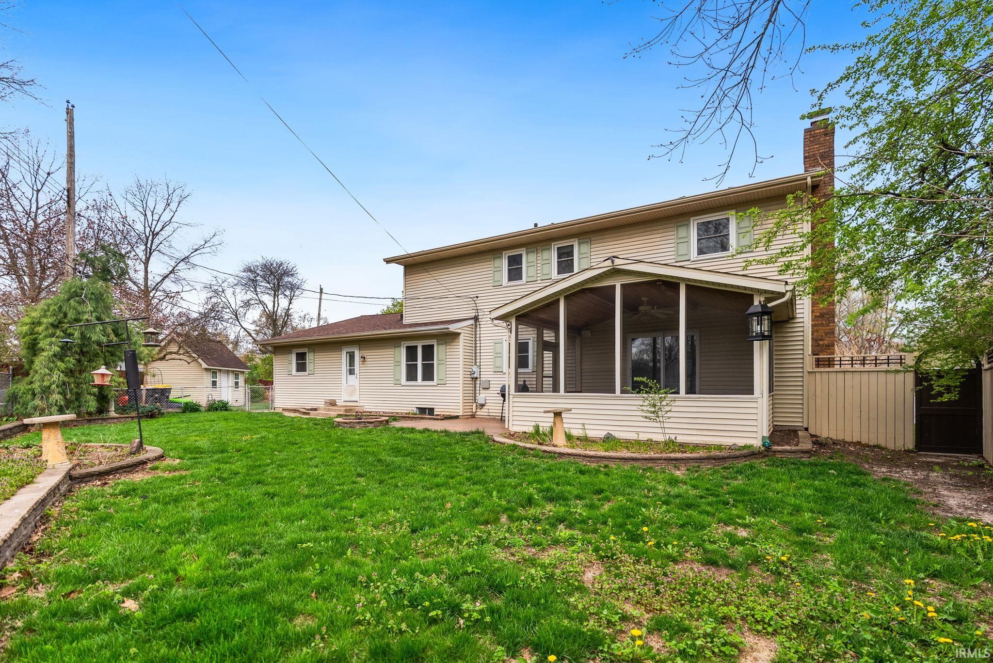 Back of property featuring a fenced backyard, a sunroom, and a chimney