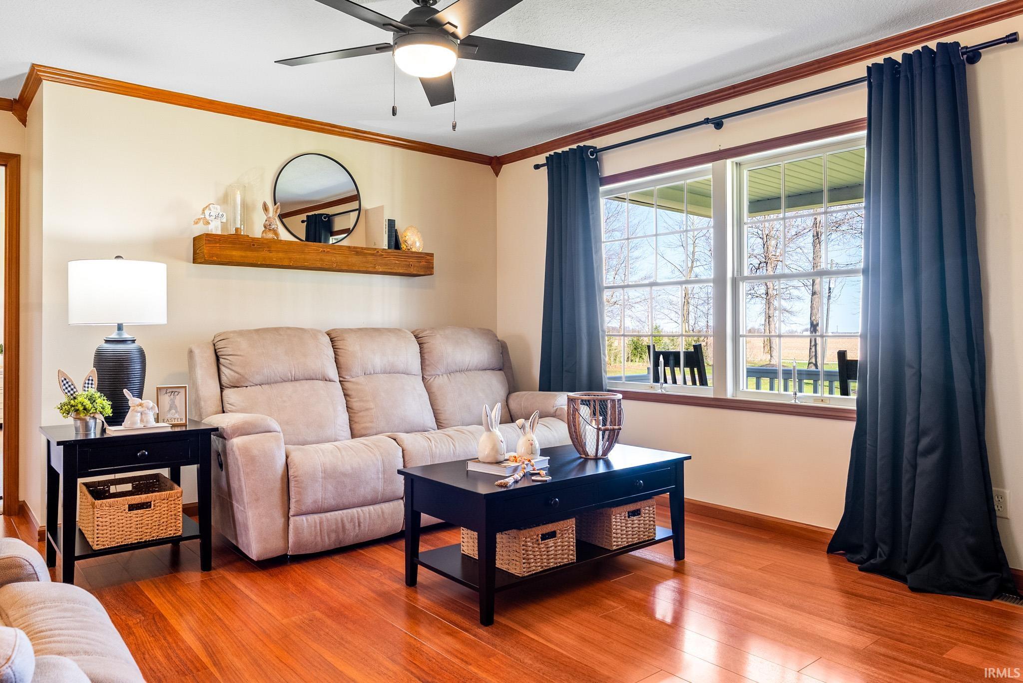 Living area with a ceiling fan, wood-type flooring, and crown molding