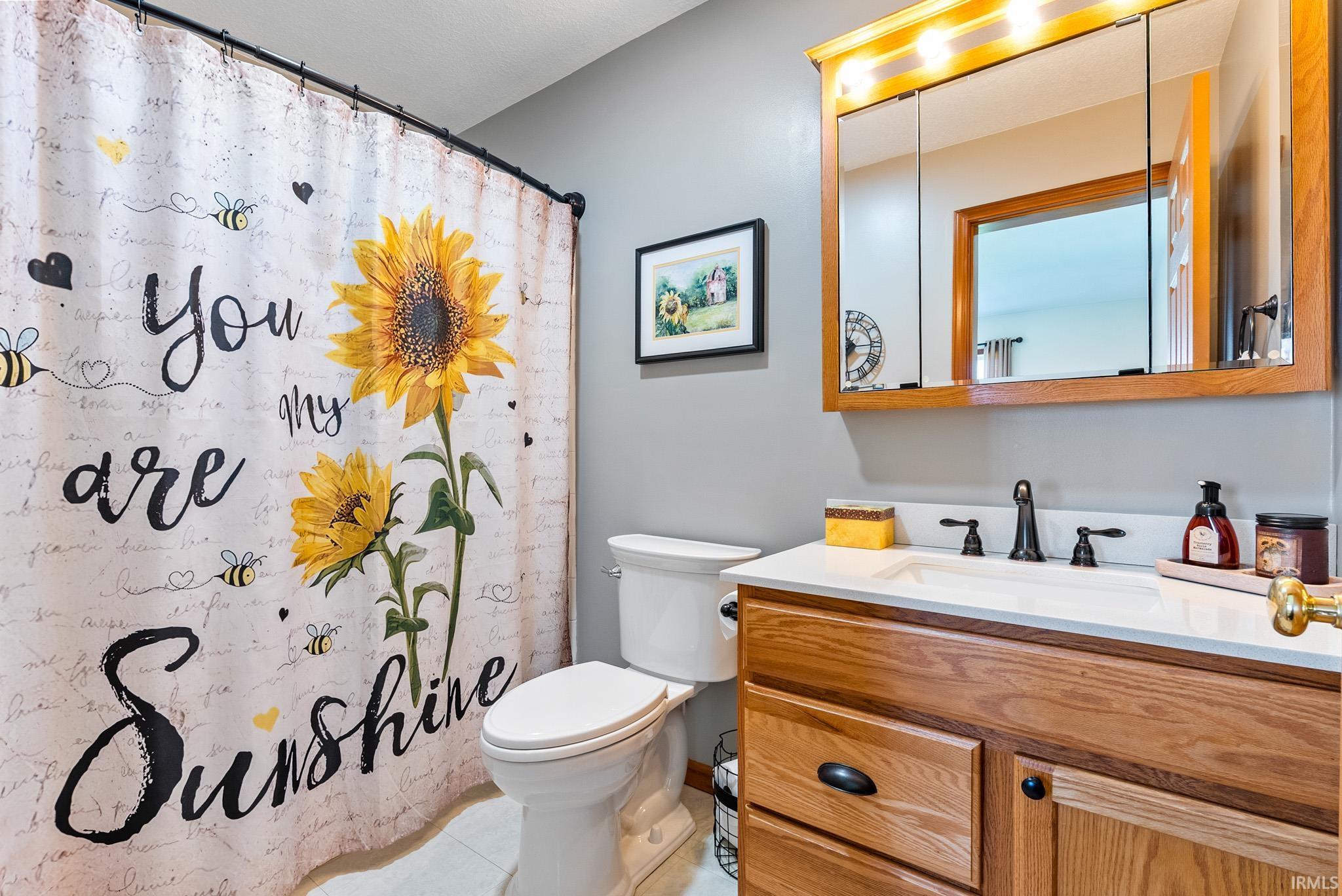 Full bathroom with curtained shower, vanity, and light tile patterned floors