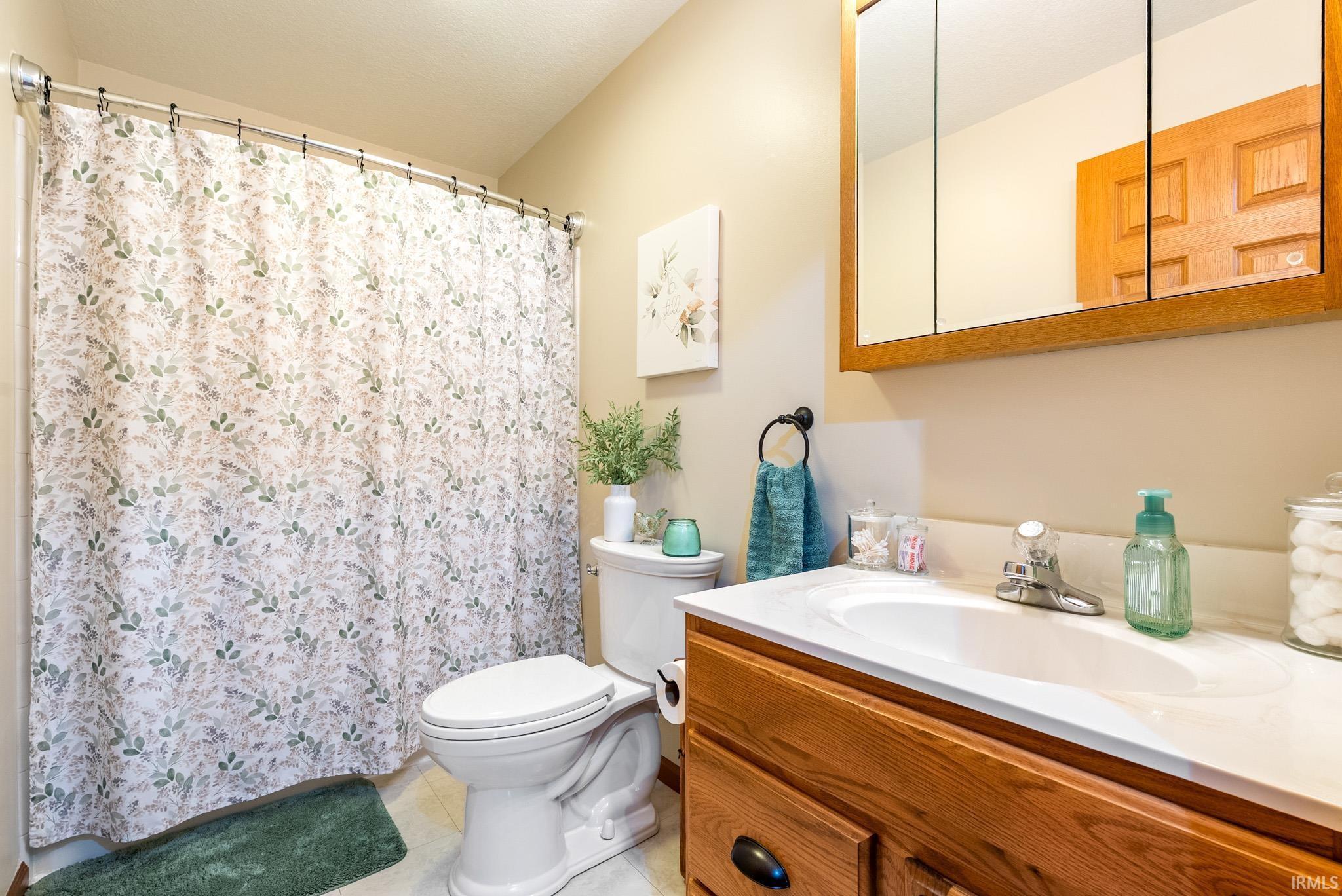 Bathroom featuring a shower with shower curtain, vanity, and light tile patterned flooring