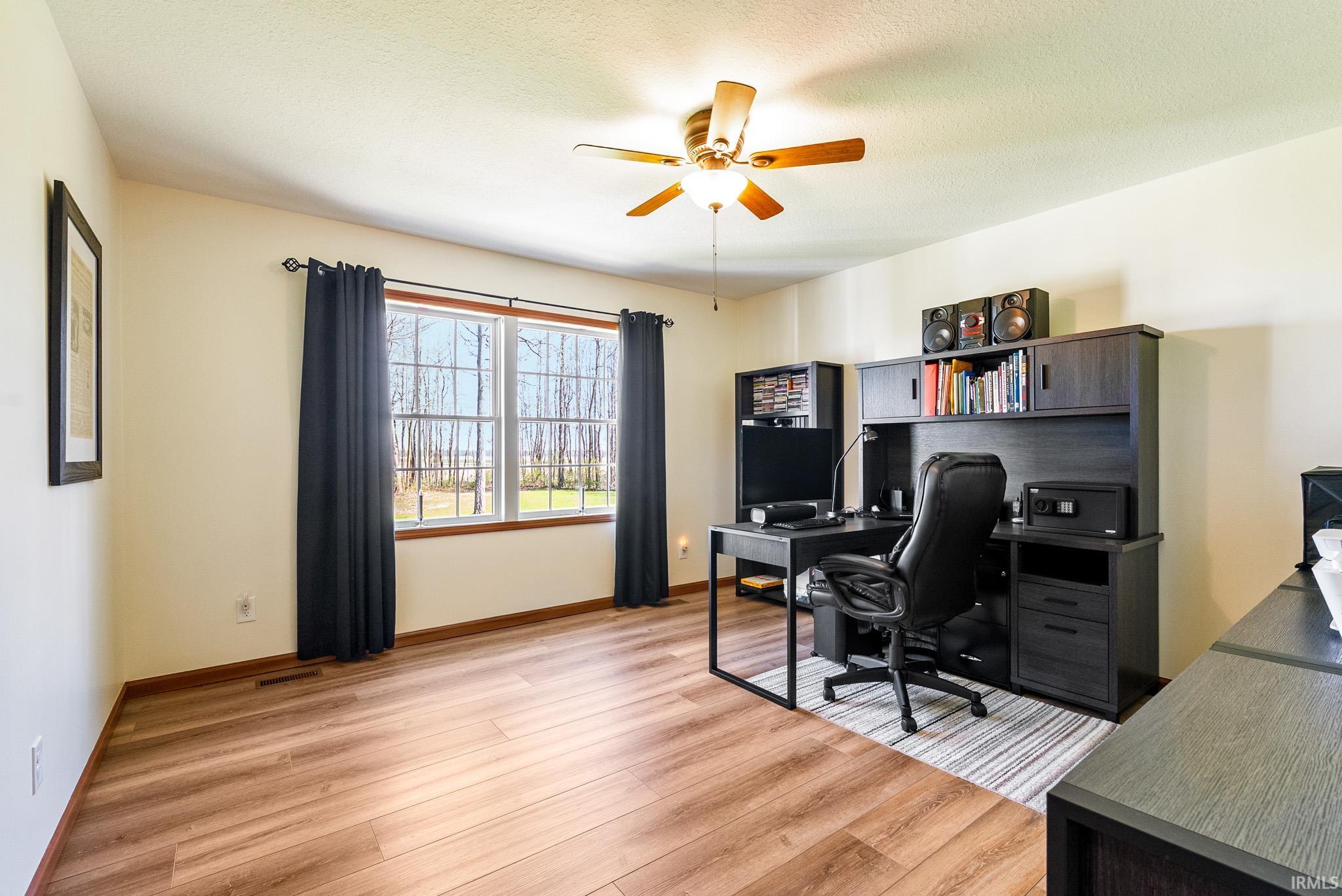 Office space with light wood-style floors, a ceiling fan, and a textured ceiling