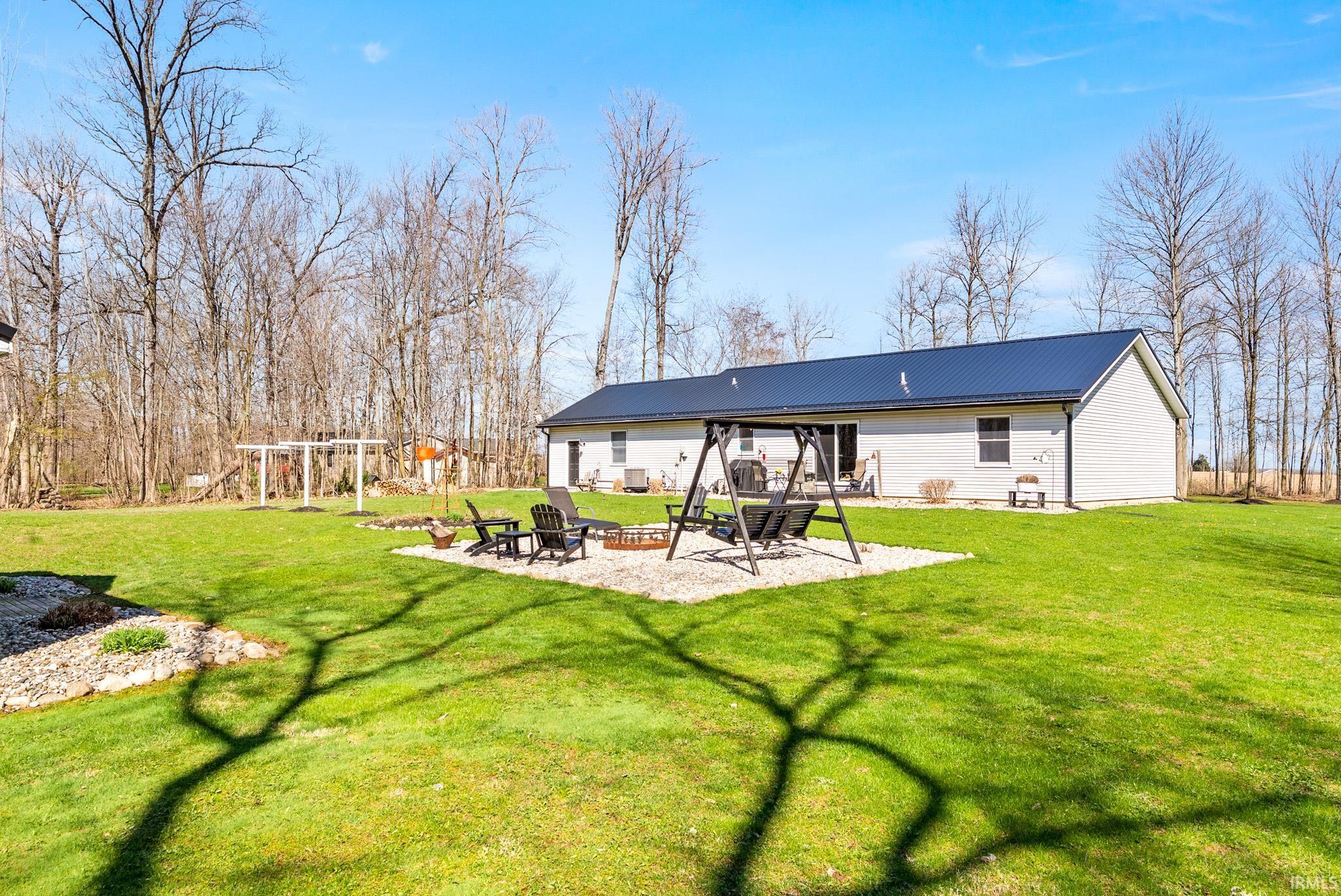Back of property with a patio area, a fire pit, a lawn, and a metal roof