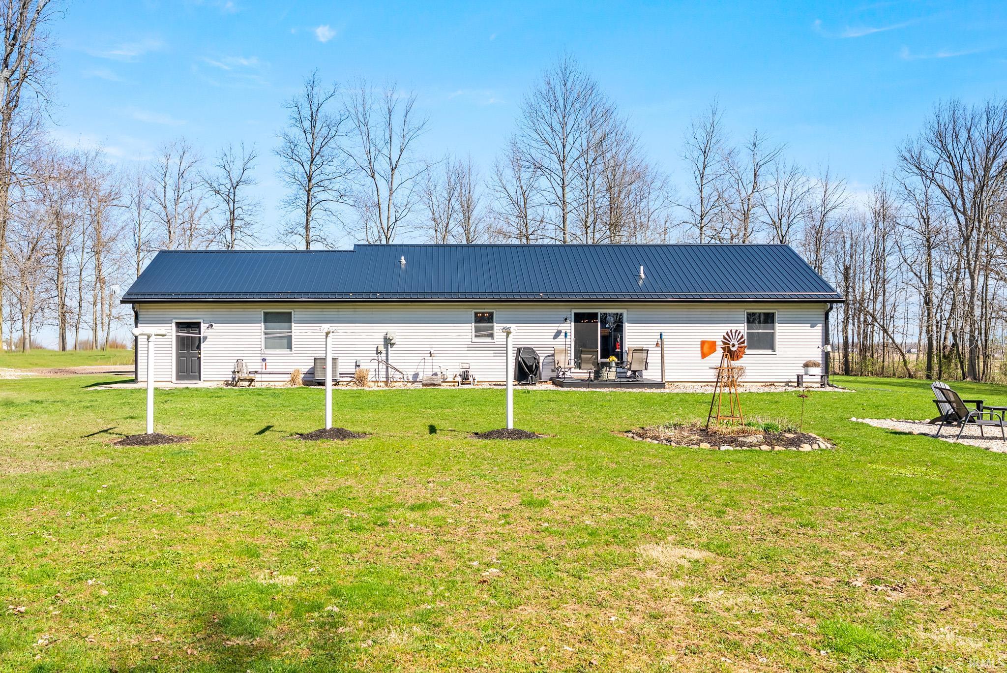 Rear view of property with a metal roof, a lawn, and a patio