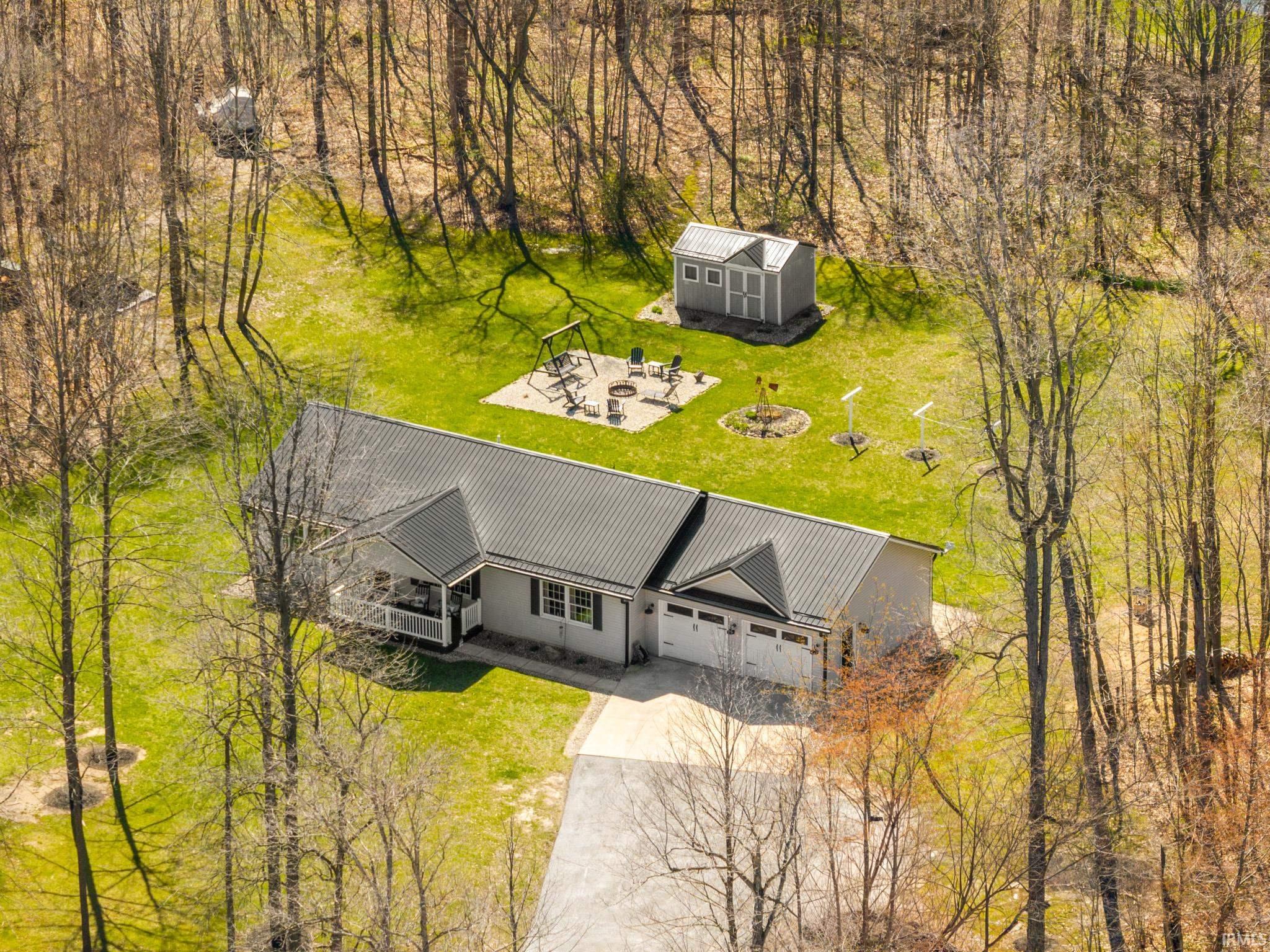 Aerial view of property and surrounding area featuring a tree filled landscape