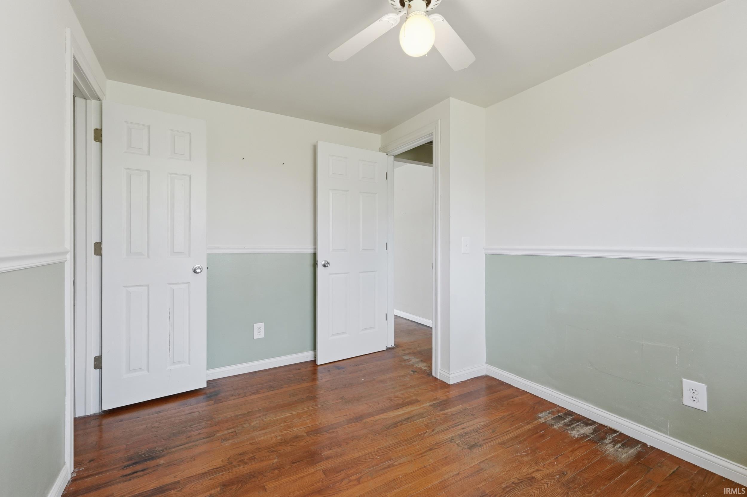 Unfurnished bedroom featuring dark wood-type flooring and a ceiling fan