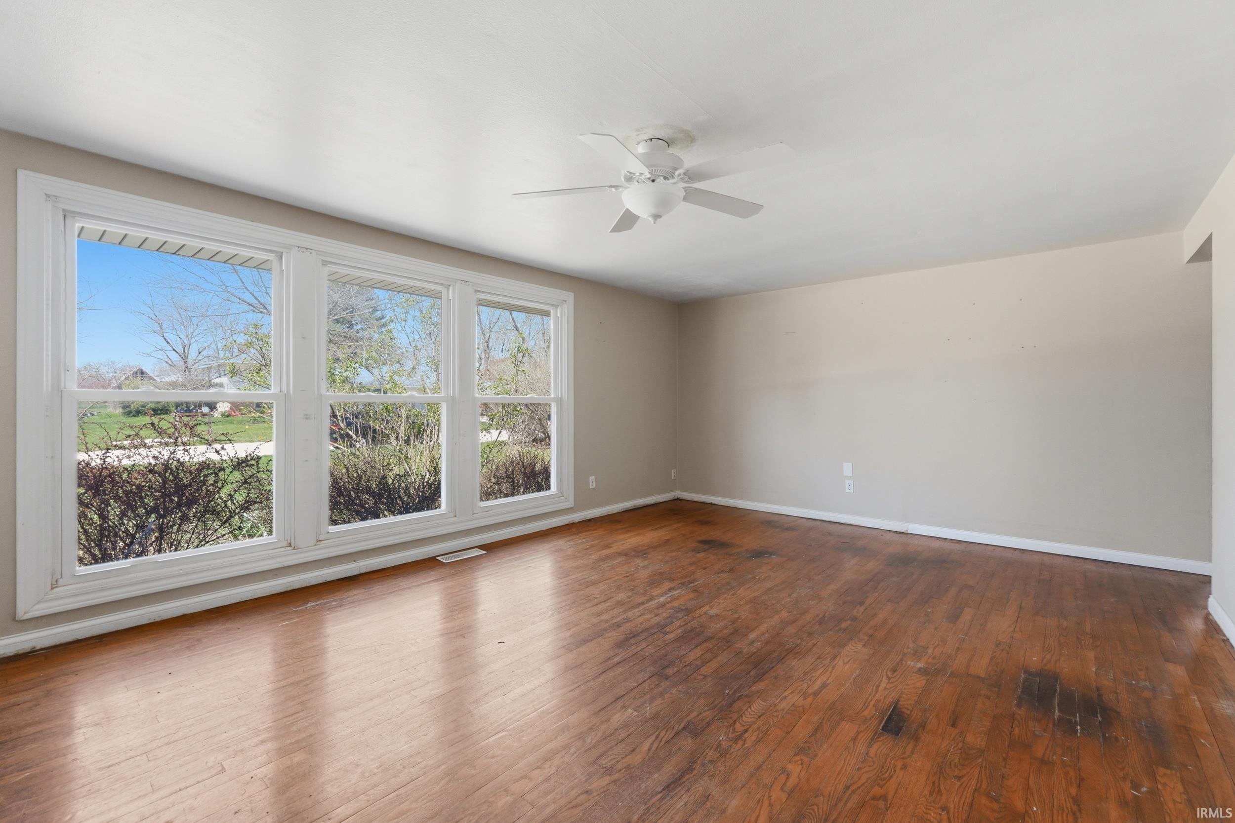 Unfurnished room with dark wood-type flooring and a ceiling fan