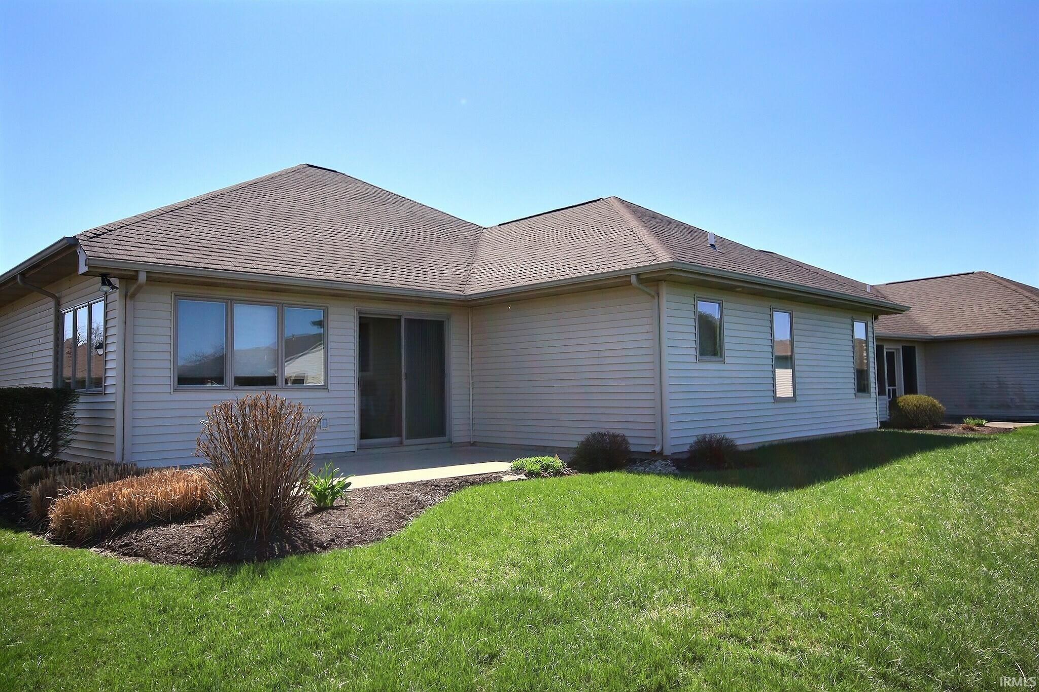 Back of property featuring a lawn, a patio area, and a shingled roof