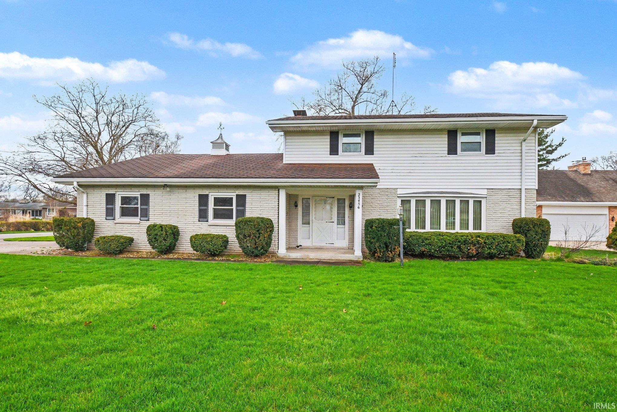 Traditional-style house featuring brick siding, a front yard, and a porch